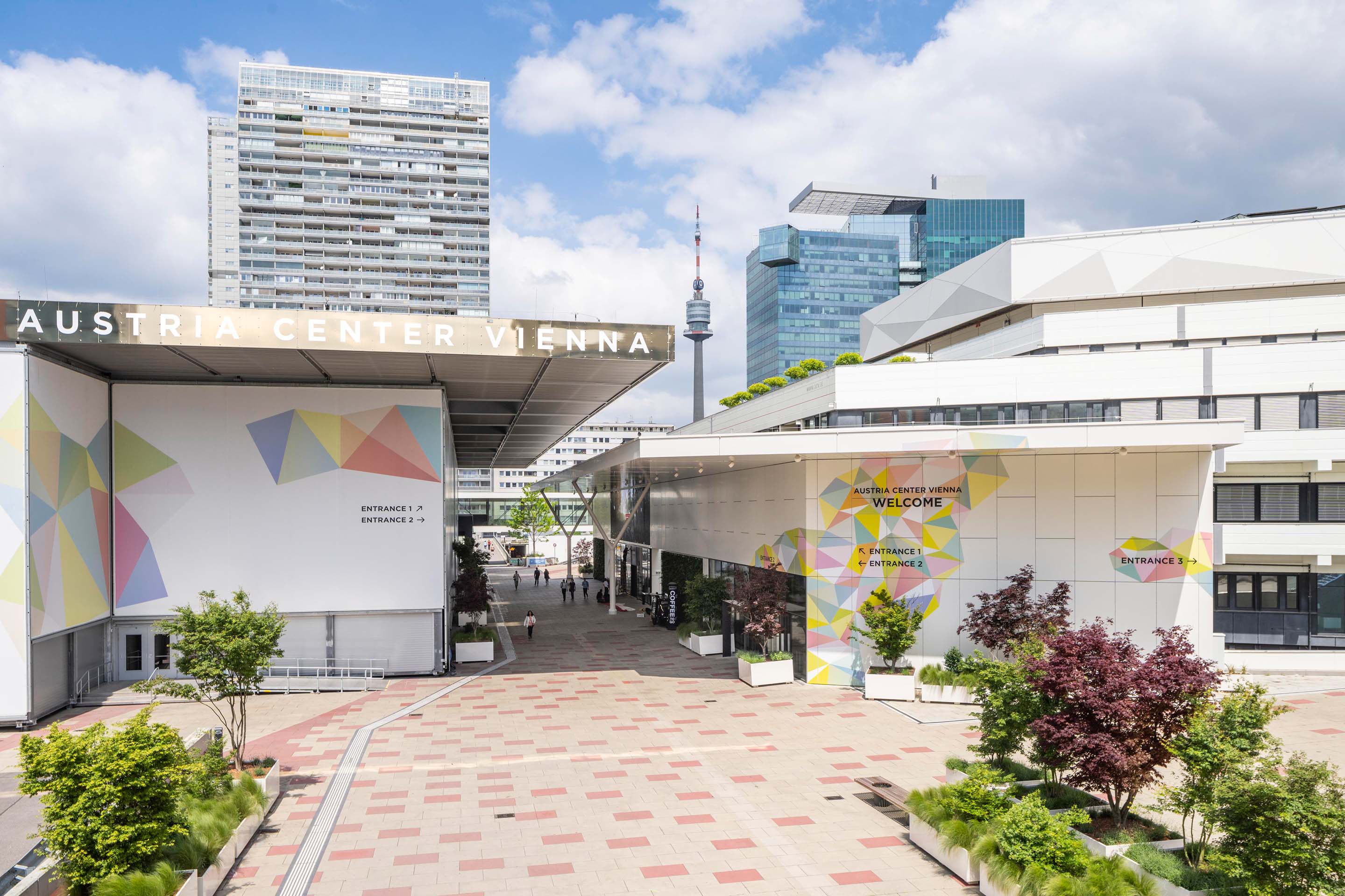 Außenansicht des Austria Center Vienna mit Begrünung und einzelnen Passanten