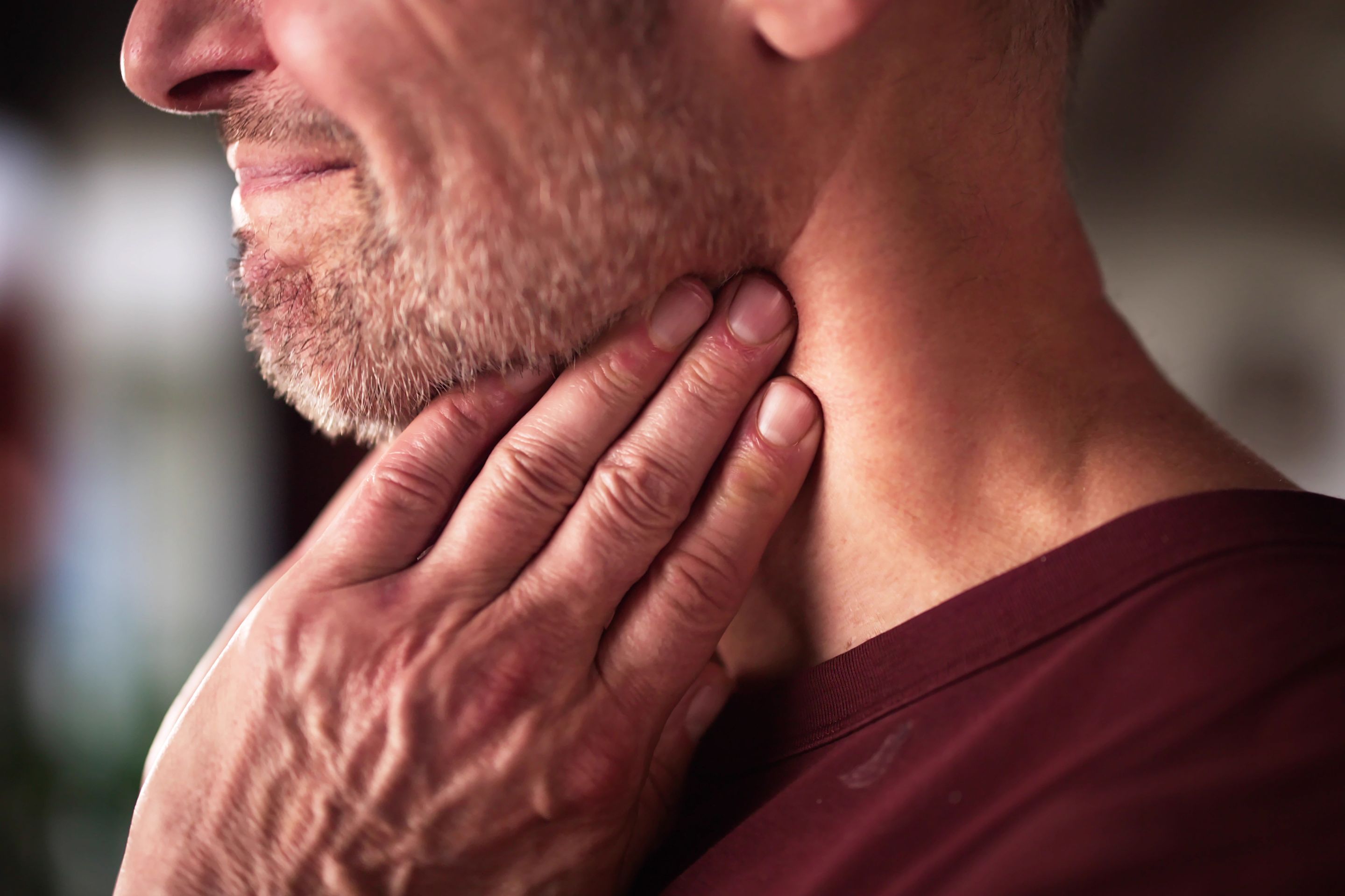 männliche Hand hält schmerzenden Hals