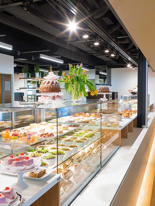 Display case with various desserts and salads in a modern café interior