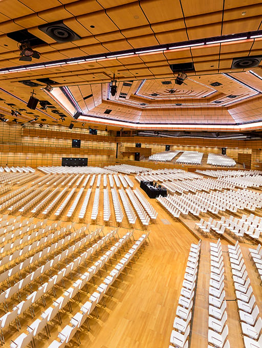 Large empty auditorium with rows of white chairs and wooden walls and ceiling