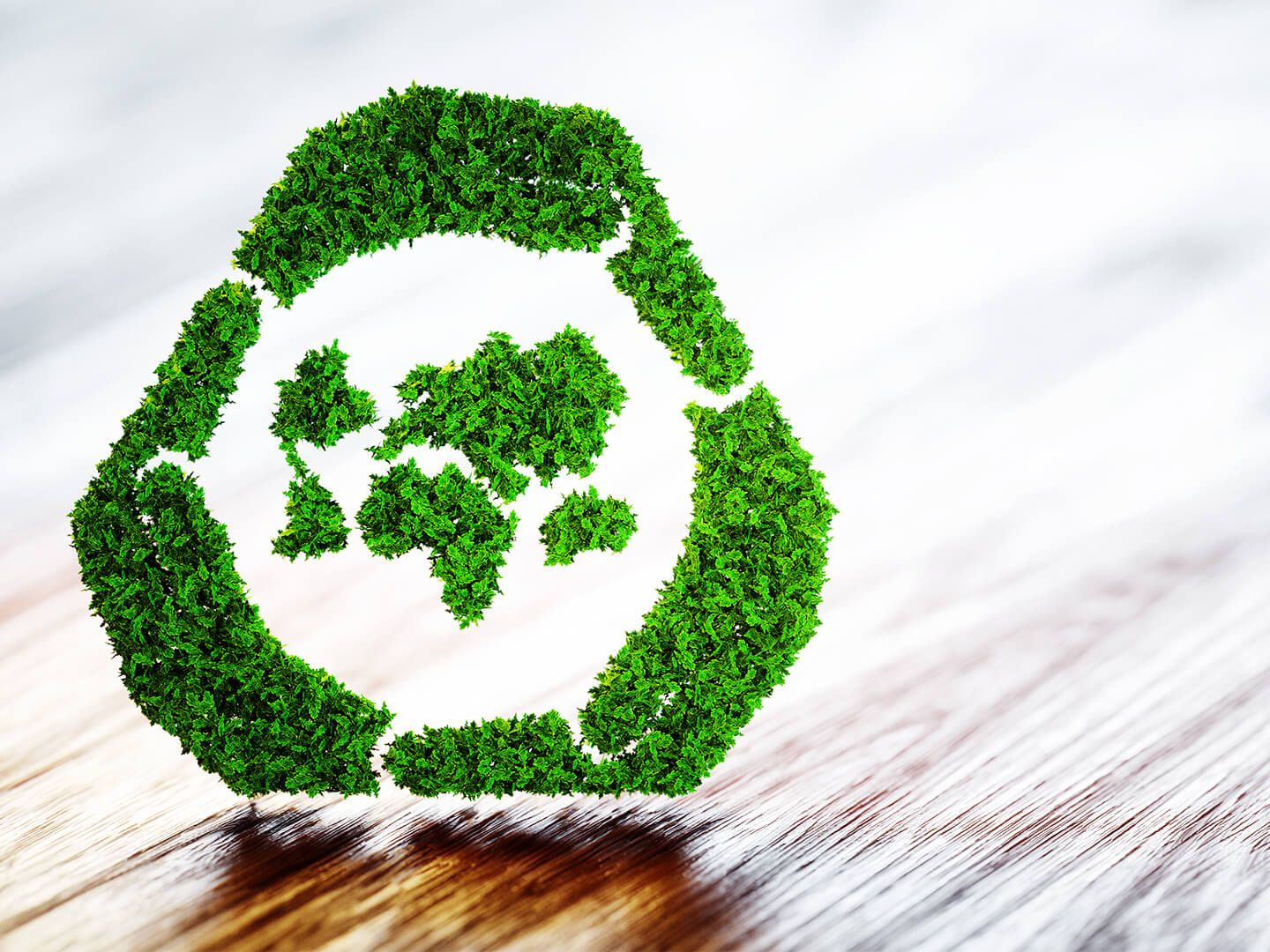Green recycling symbol made of leaves on a wooden surface