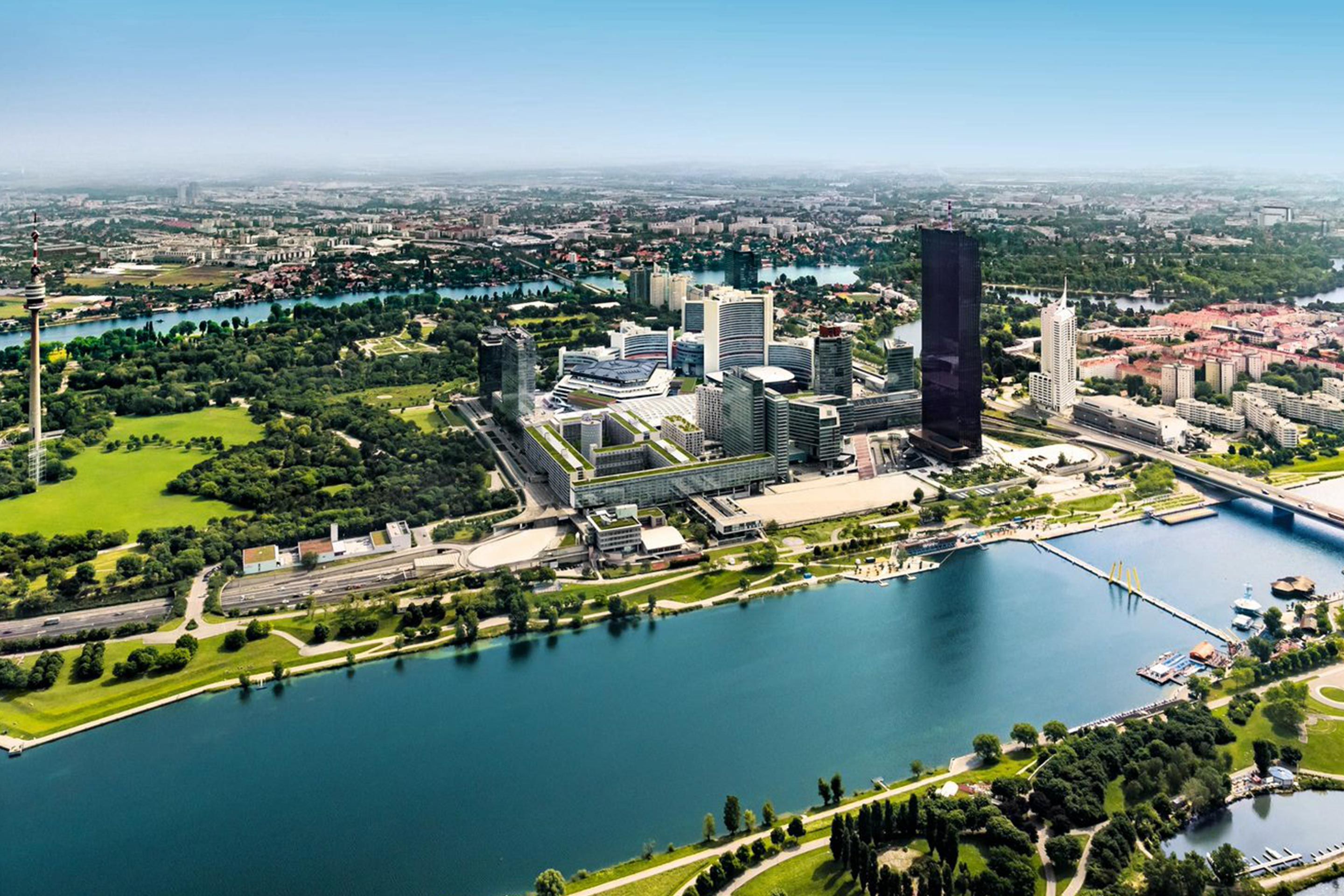 Aerial view of a city skyline with river, green parks, and modern buildings.
