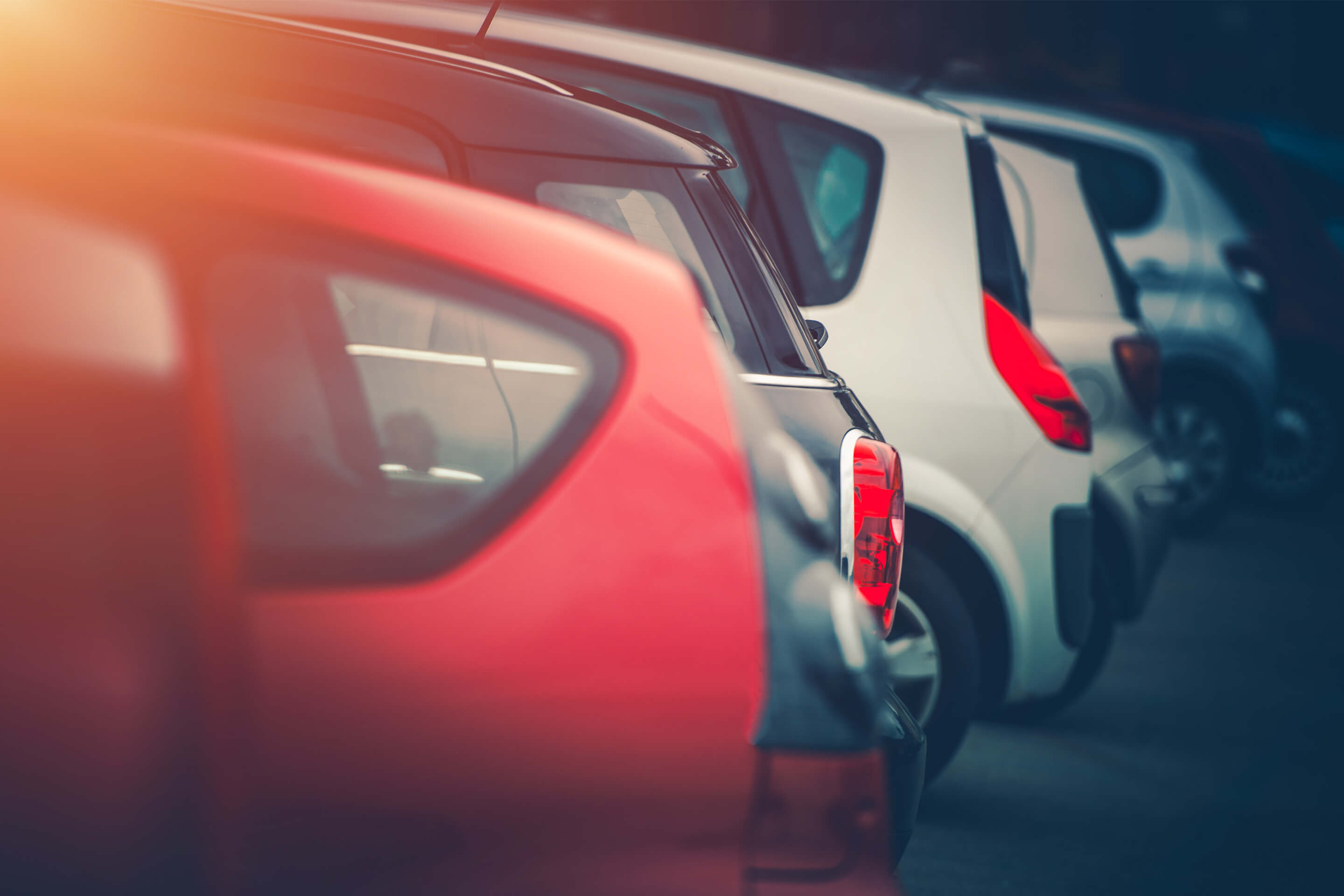 Heckansichten mehrerer parkender Autos in einer Reihe bei gedämpftem Licht