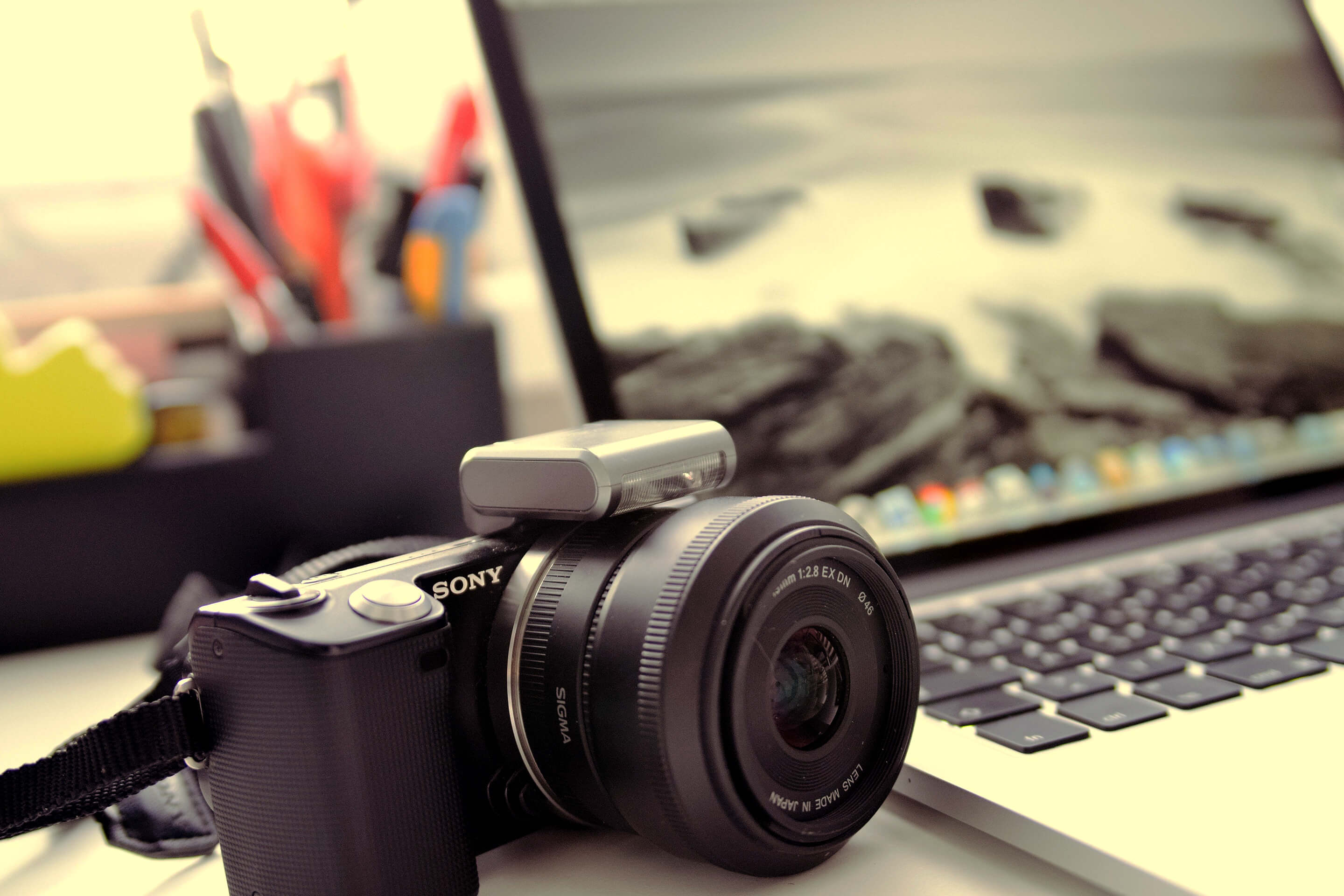 Sony camera with Sigma lens in front of a laptop keyboard and screen