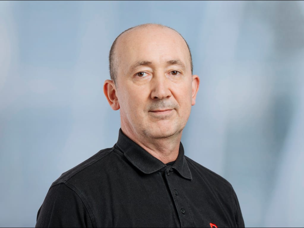 Man wearing a black collared shirt against a light blue background