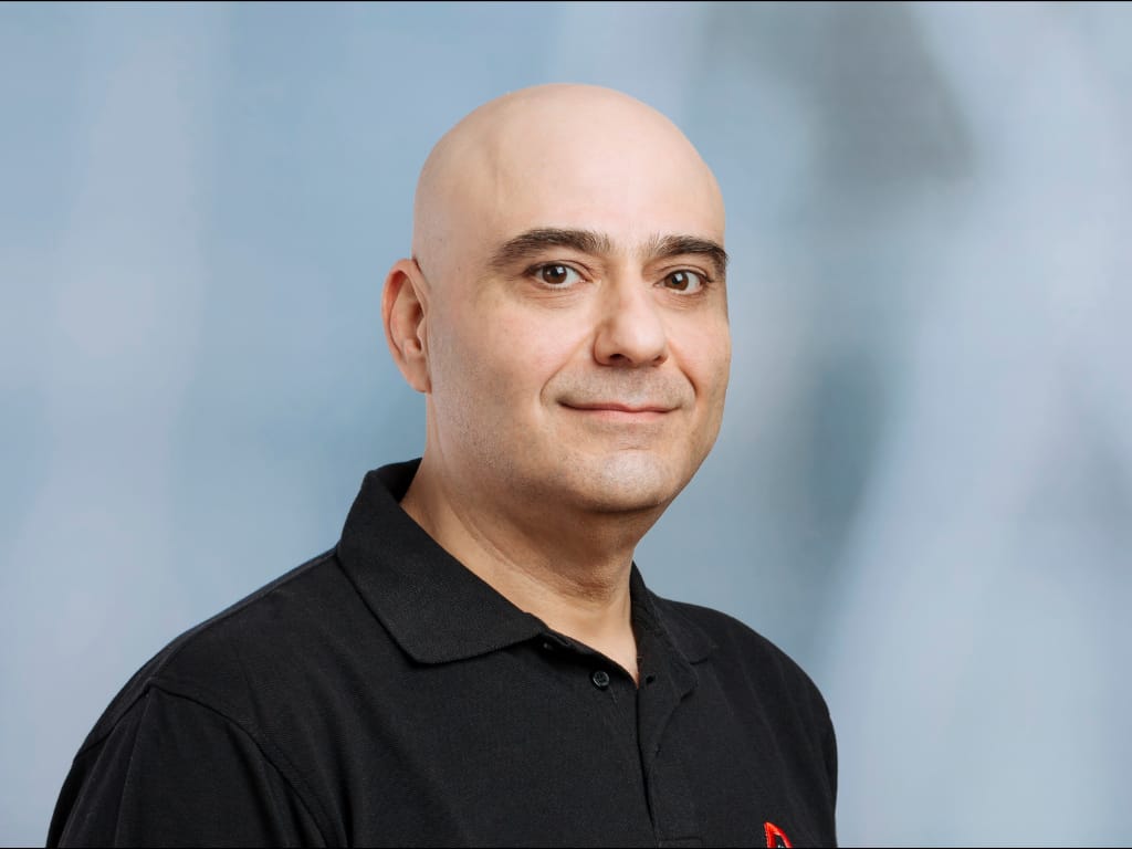 Person wearing a black collared shirt against a light blue background