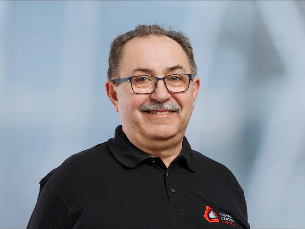 Man wearing black polo shirt with Austria Center Vienna logo on light blue background