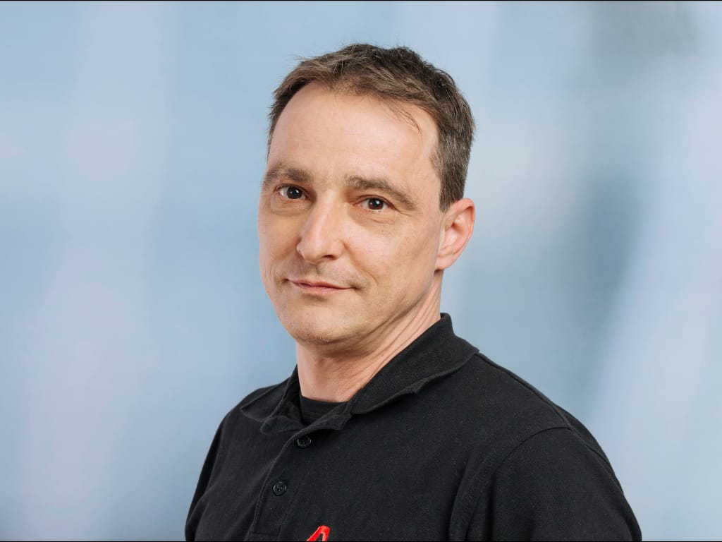 Man wearing a black collared shirt against a light blue background