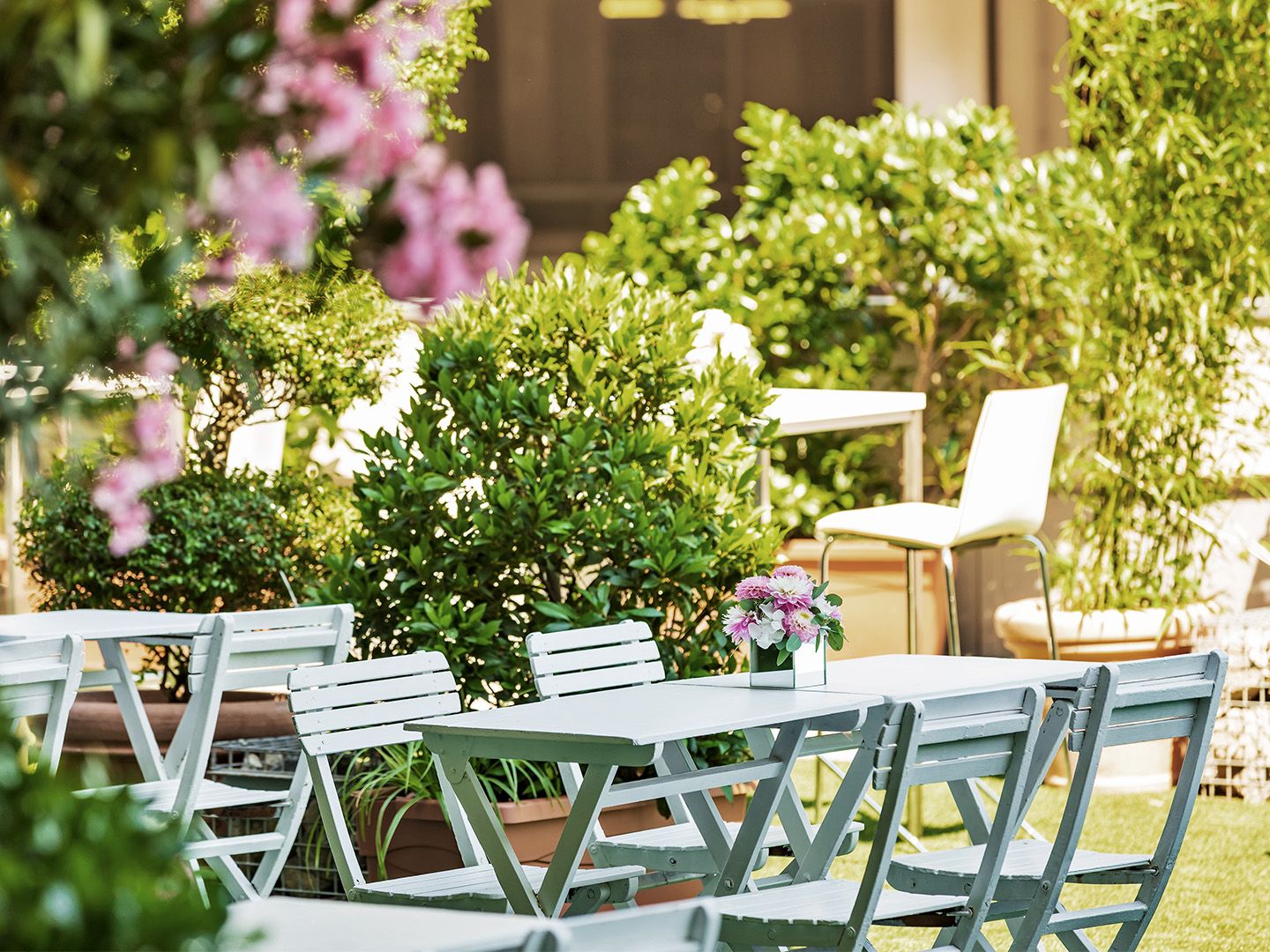 Outdoor white wooden table and chairs with a small flower arrangement on the table