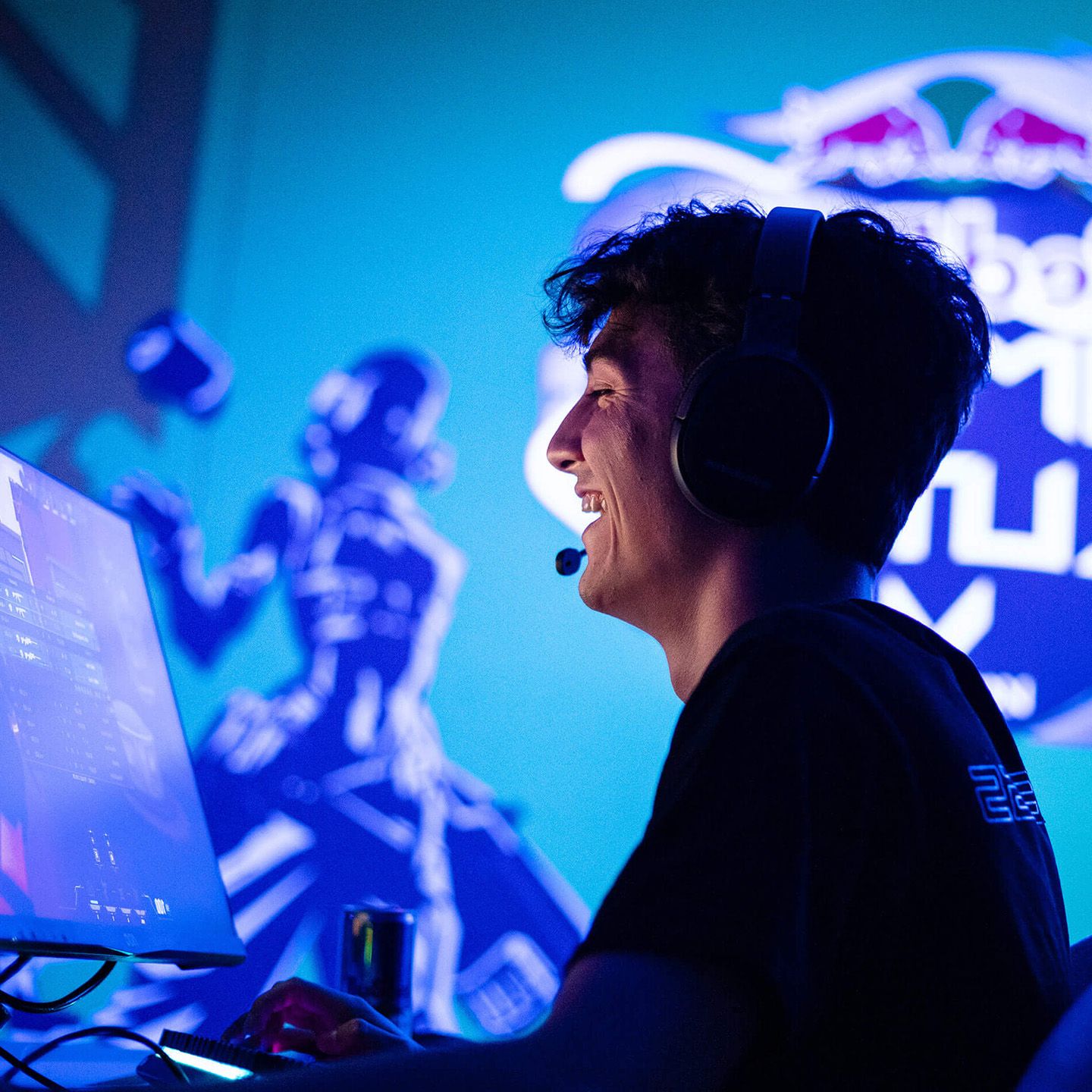 Person wearing headphones using a computer with a gaming-themed background and logo visible