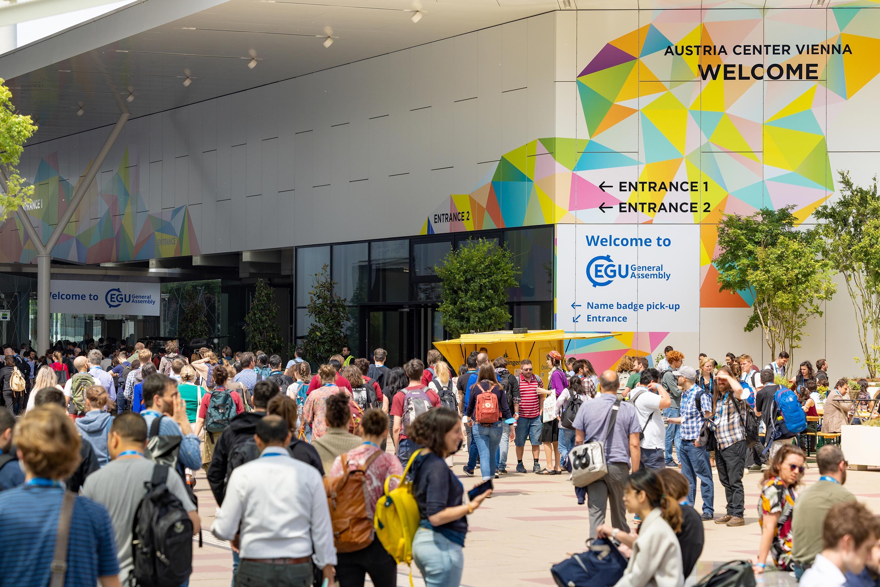 Menschenmenge vor dem Austria Center Vienna mit Hinweisschildern zum Eingang und zur EGU General Assembly