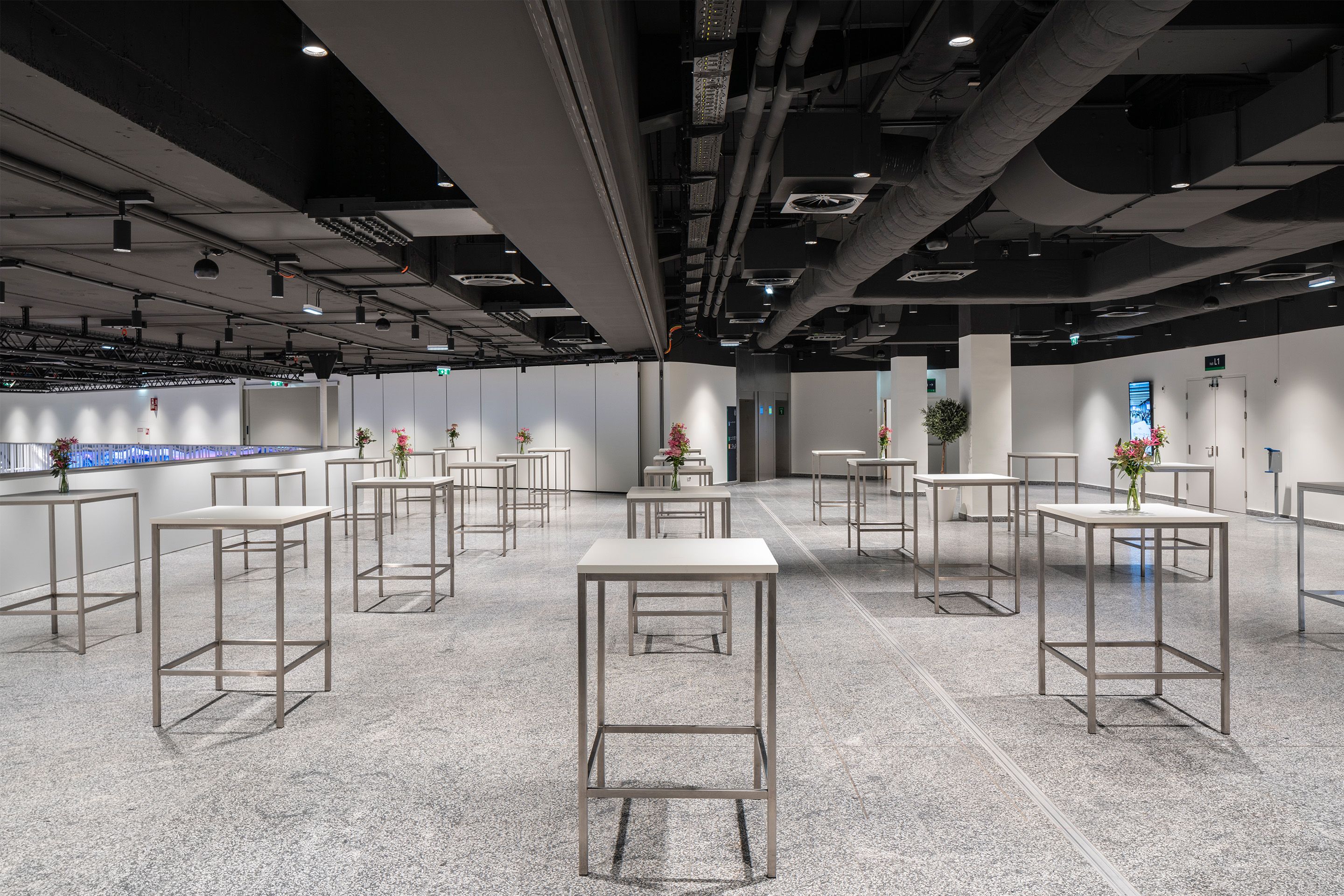 Foto: weißes Foyer mit Hochtischen, Blumenschmuck, dunkle Decke
