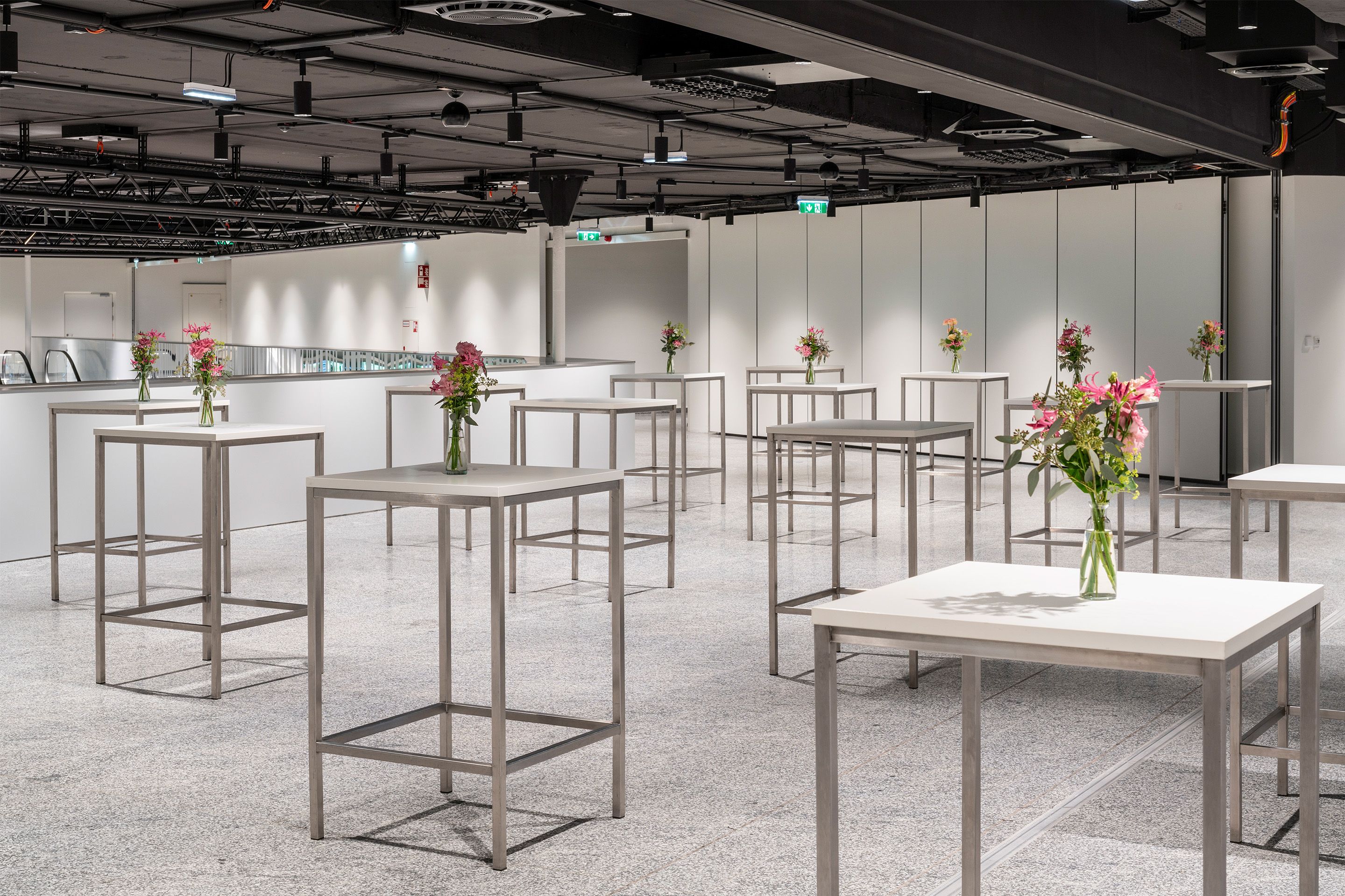 Foto: weißes Foyer mit Hochtischen, Blumenschmuck, dunkle Decke