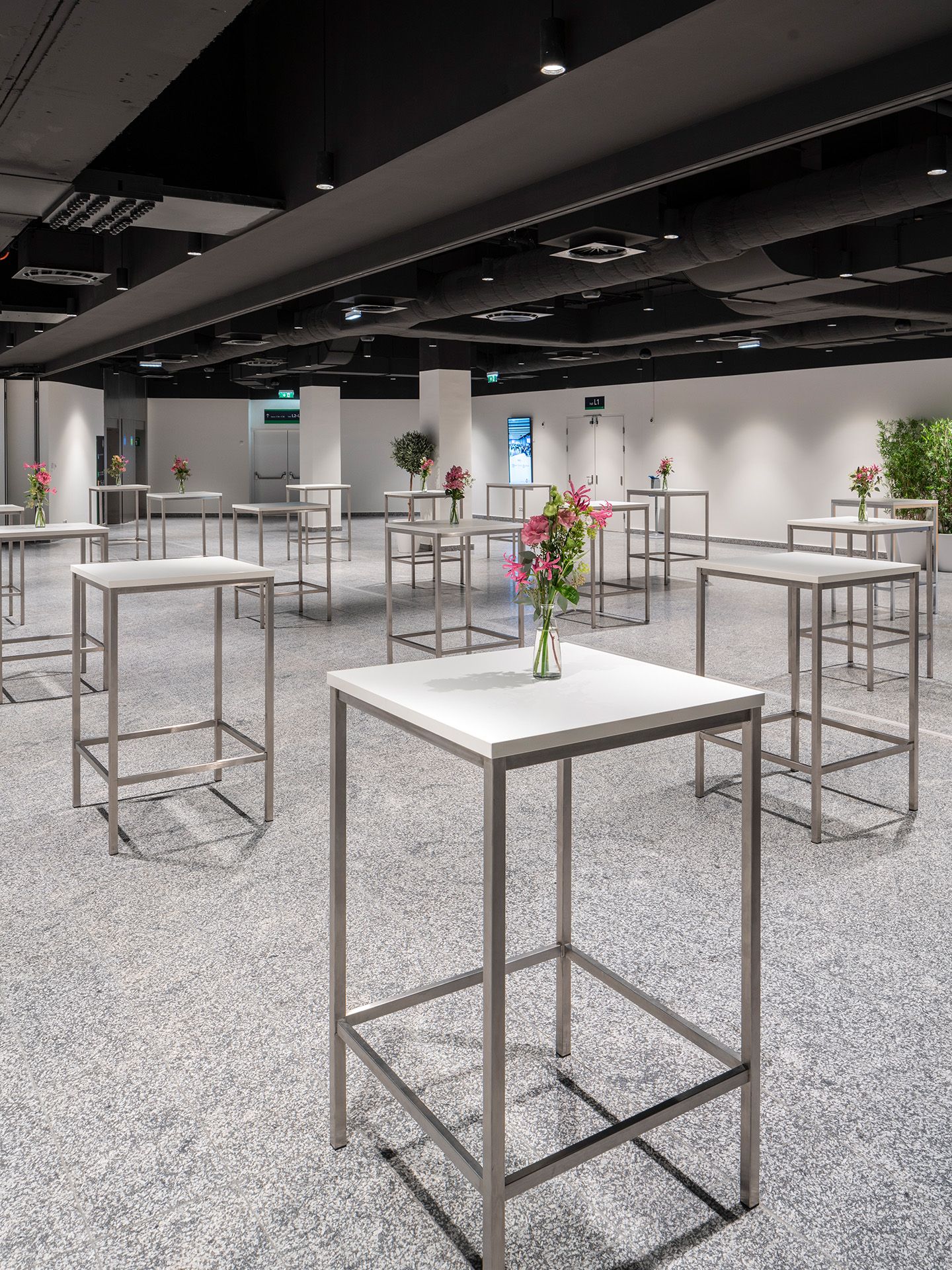 Foto: weißes Foyer mit Hochtischen, Blumenschmuck, dunkle Decke