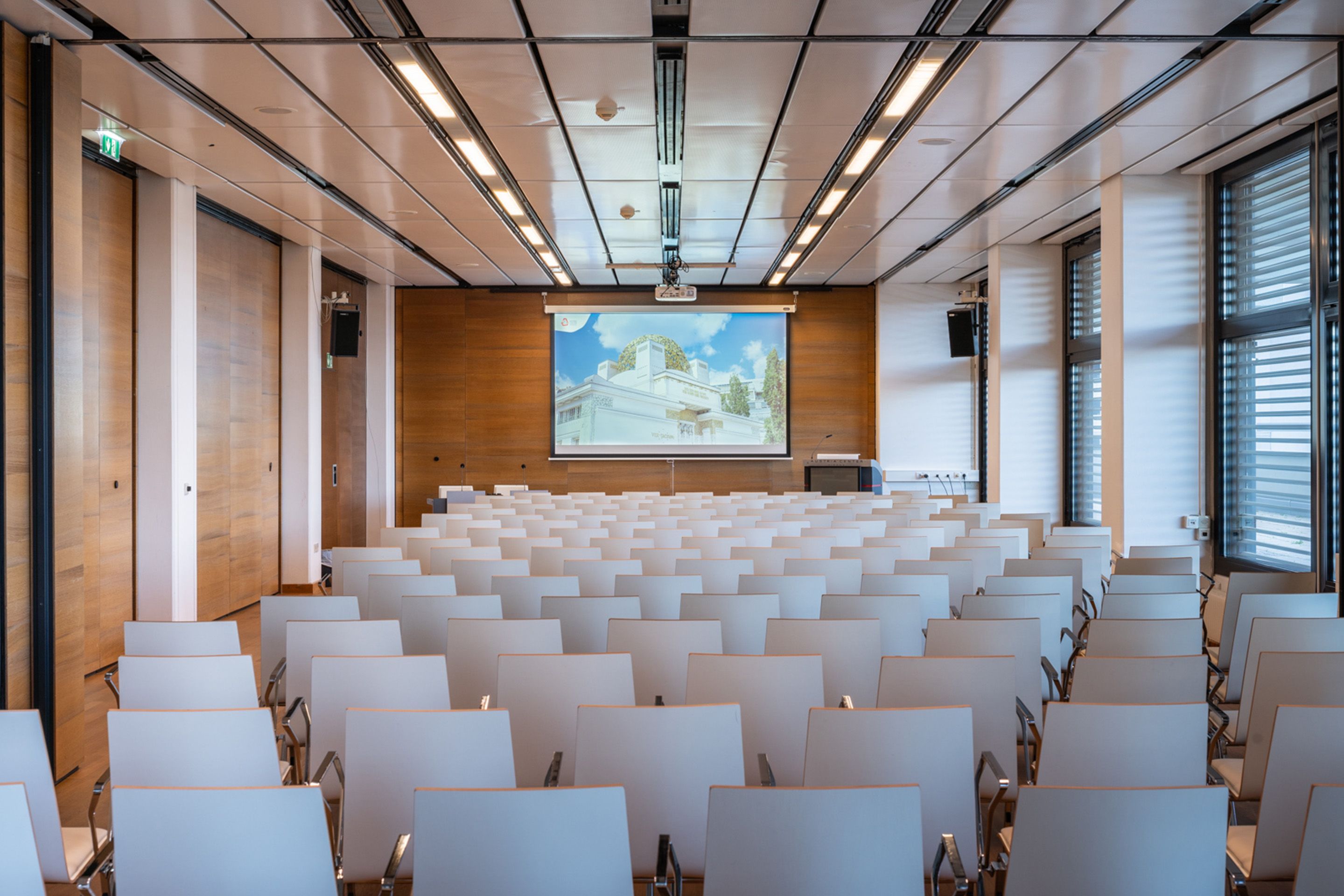 Leerer Konferenzraum mit weißen Stühlen und Leinwand mit Gebäudeabbildung