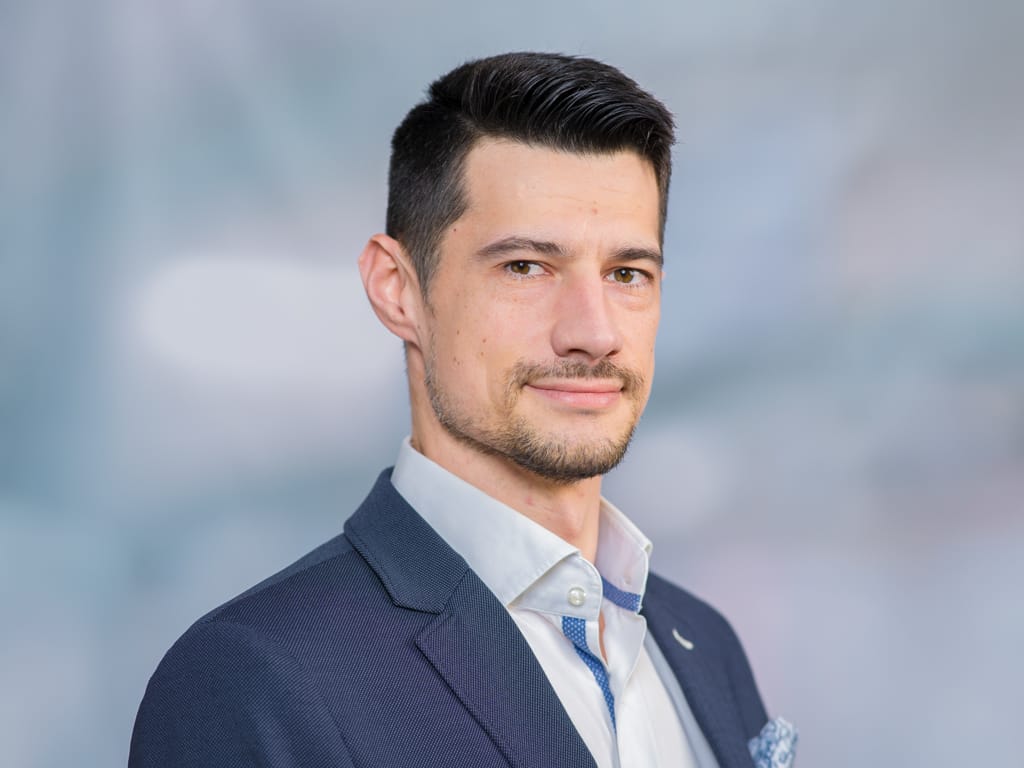 Man wearing a dark blue suit jacket and white shirt with blue trim on collar and placket