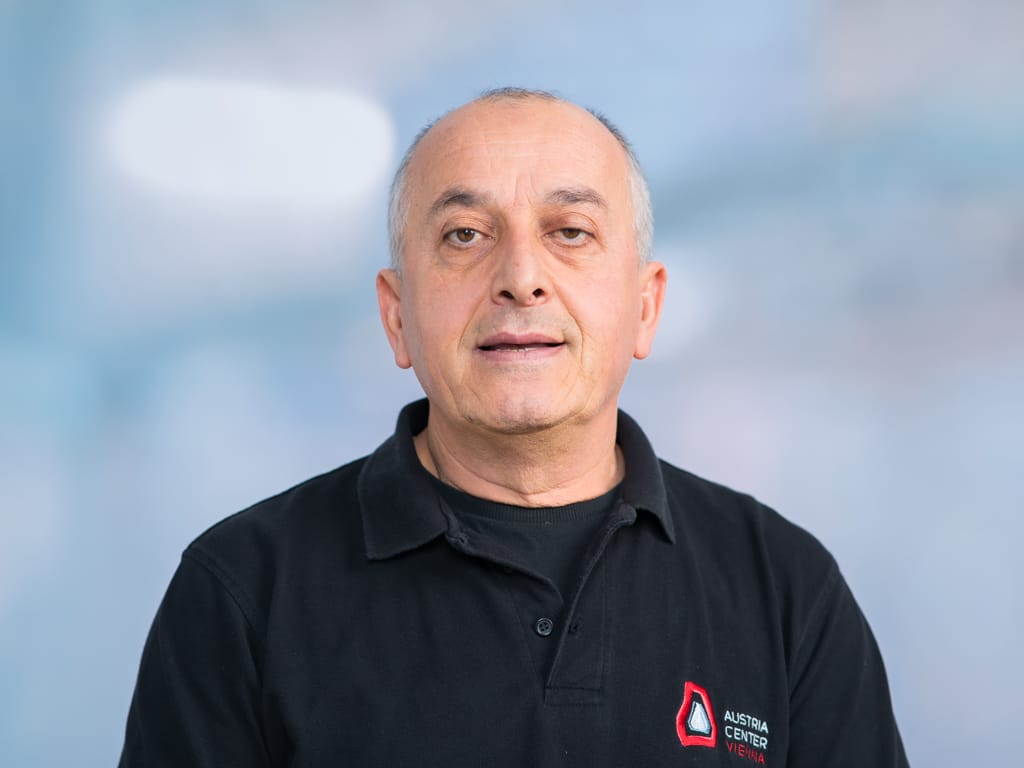 Man wearing a black polo shirt with Austria Center Vienna logo on the chest