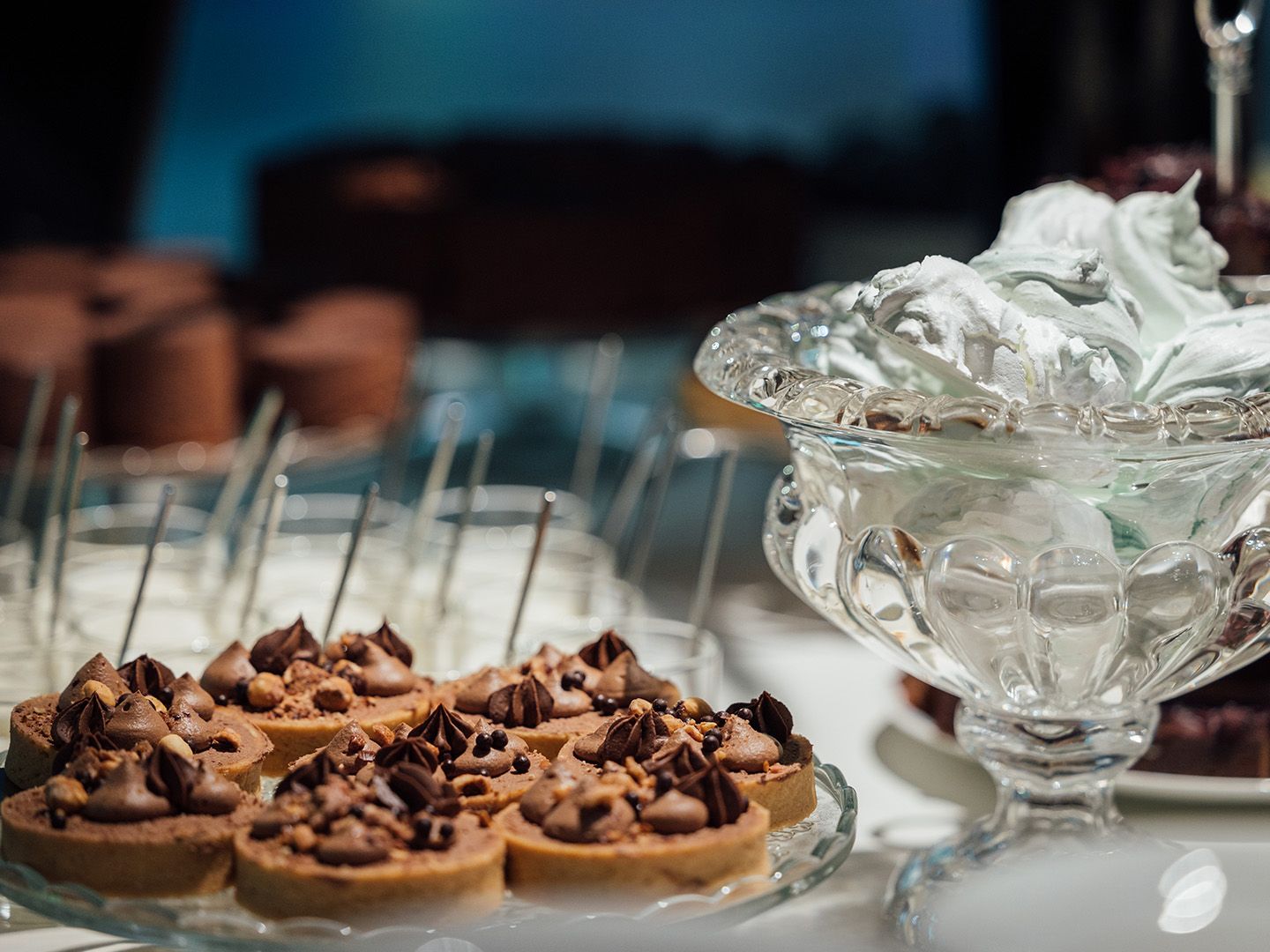 Schokoladen-Törtchen auf Glasplatte und Schüssel mit weißer Creme auf Tisch