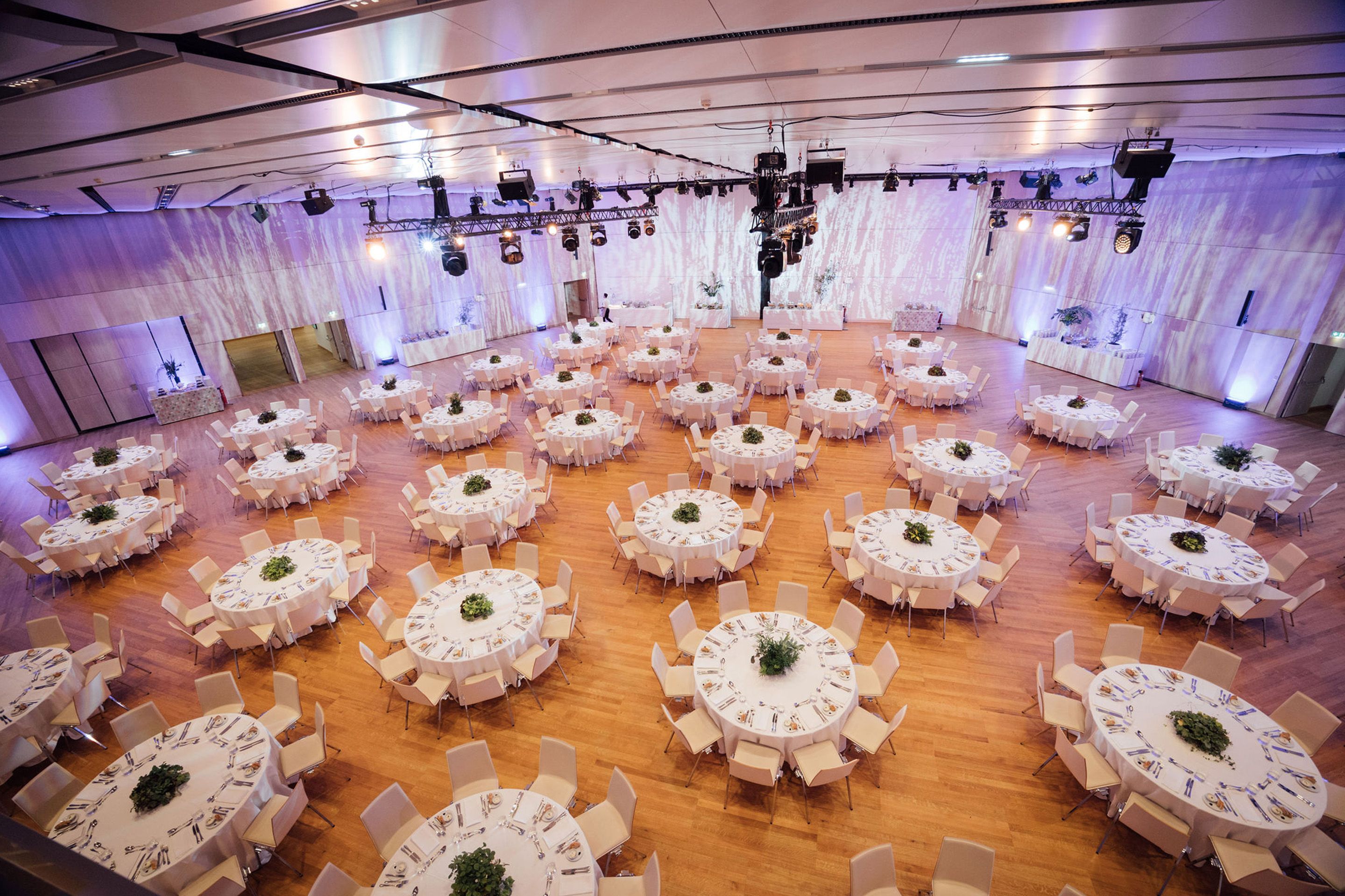Large event hall with round tables set for dining and chairs arranged around them