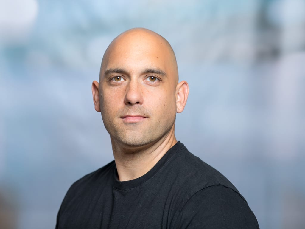 Person wearing a black t-shirt against a blurred blue-gray background