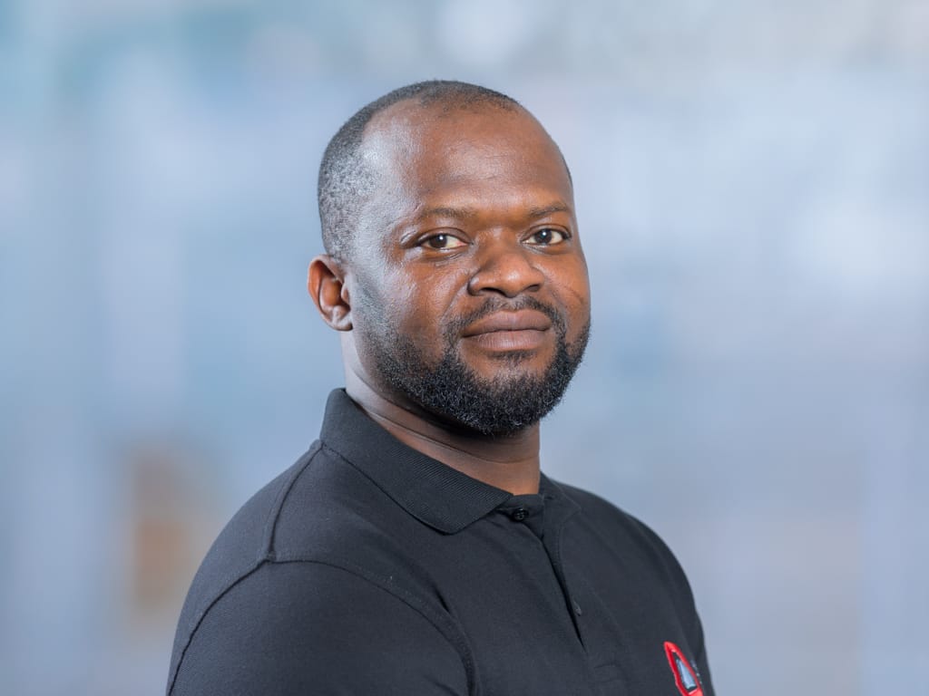 Person wearing a black polo shirt with a red and white embroidered logo on the chest