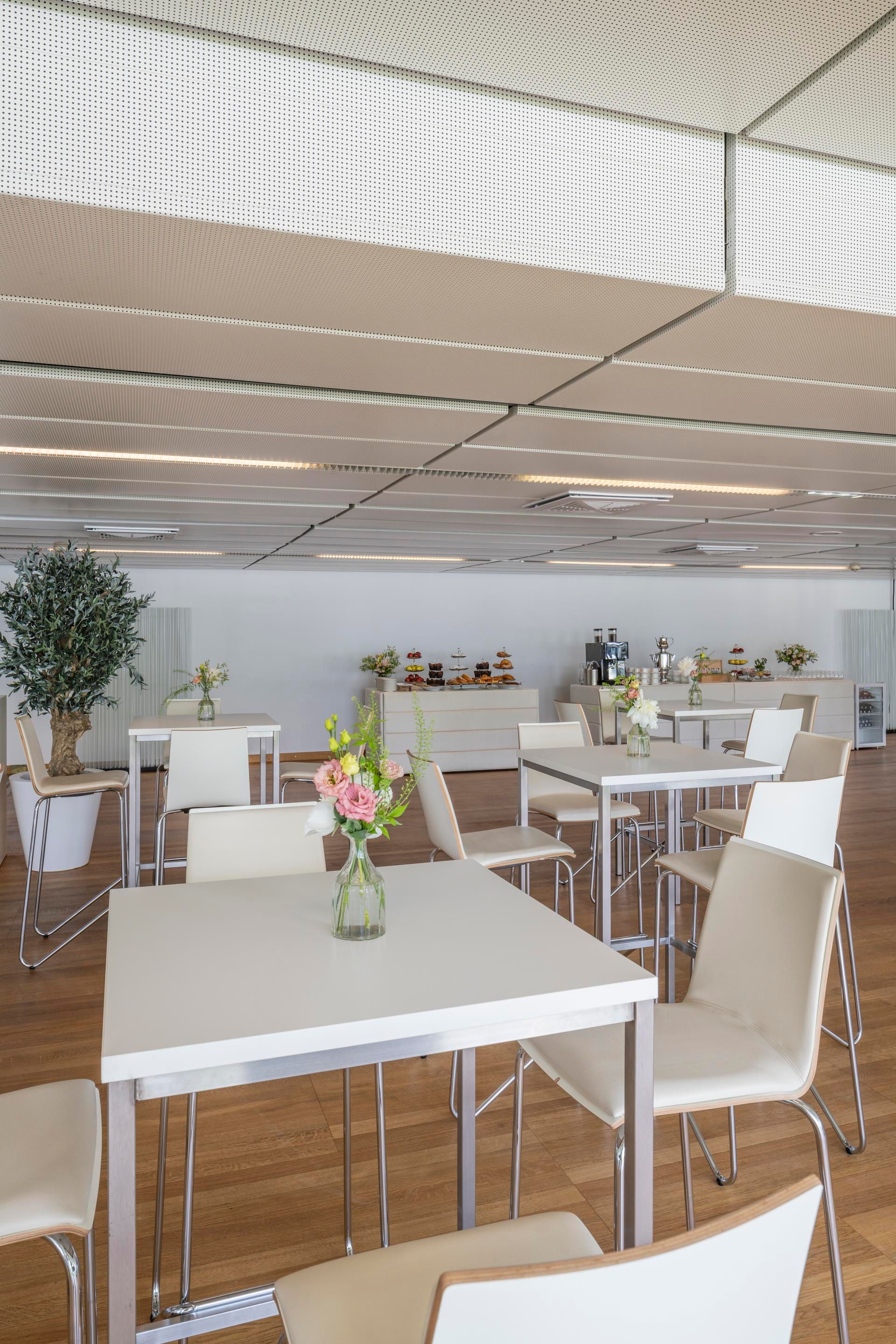 Modern dining area with white tables, chairs, and flower vases on tables