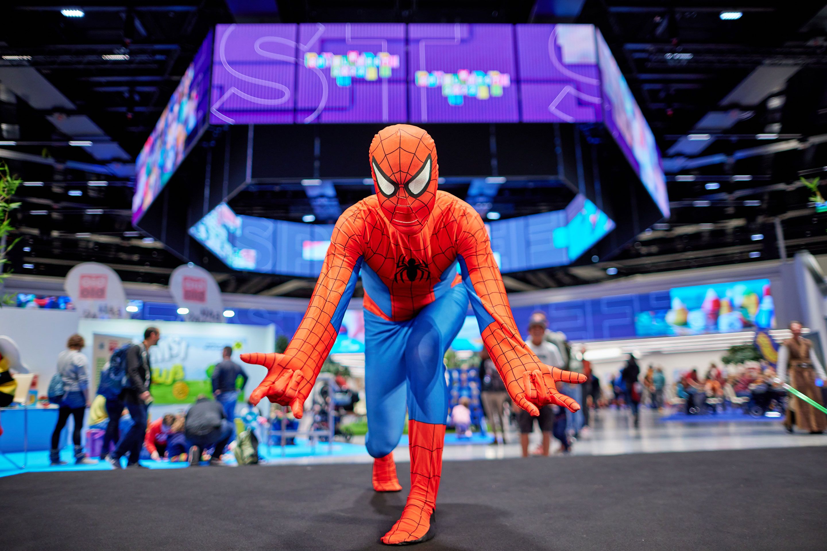 Person in Spider-Man-Kostüm in einer Pose auf einer Messe oder Veranstaltungshalle