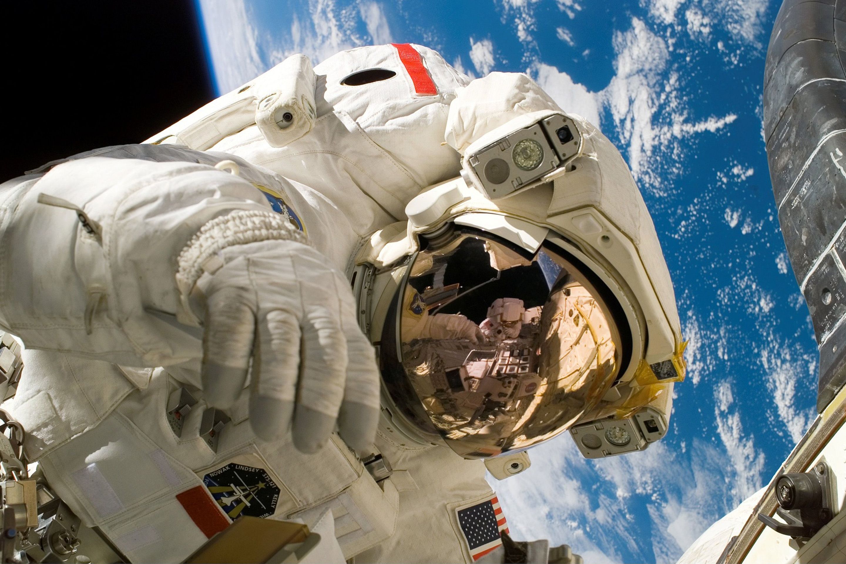 Astronaut in Raumanzug vor der Erde mit Spiegelung im Helmvisier