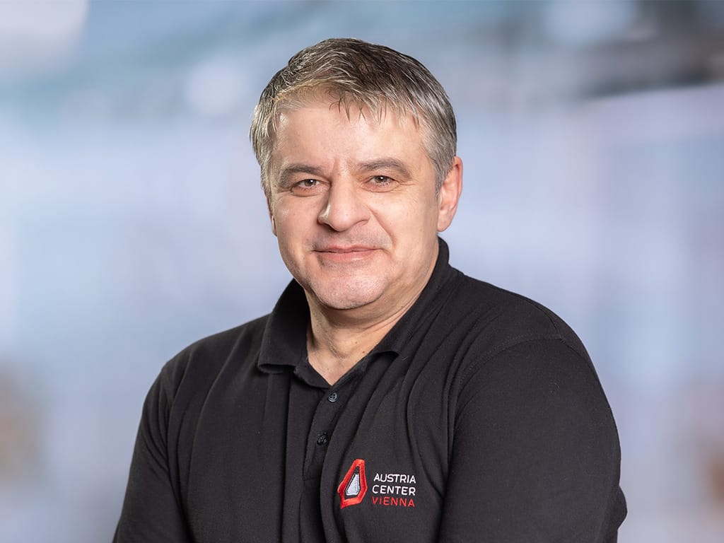 Person wearing black polo shirt with Austria Center Vienna logo on chest