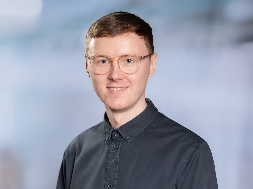 Person wearing a dark button-up shirt against a blurred light background