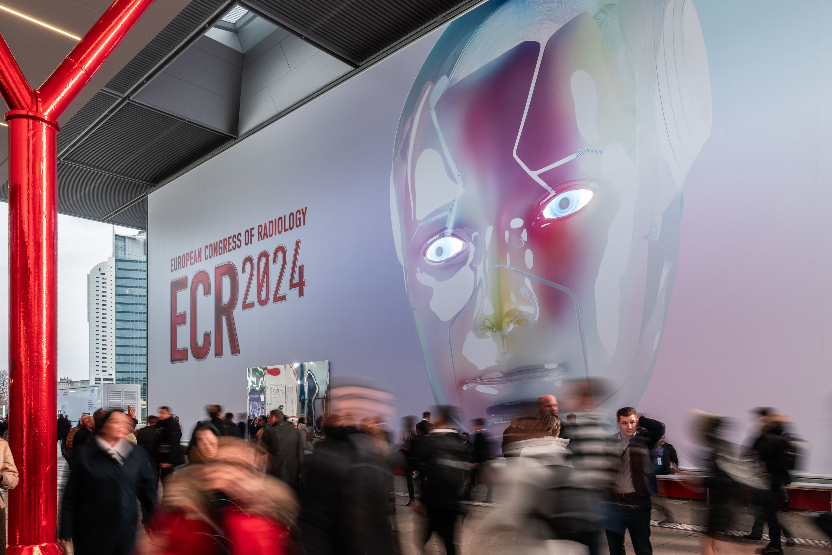 Large digital face artwork with text "European Congress of Radiology ECR 2024" on a wall above a crowd