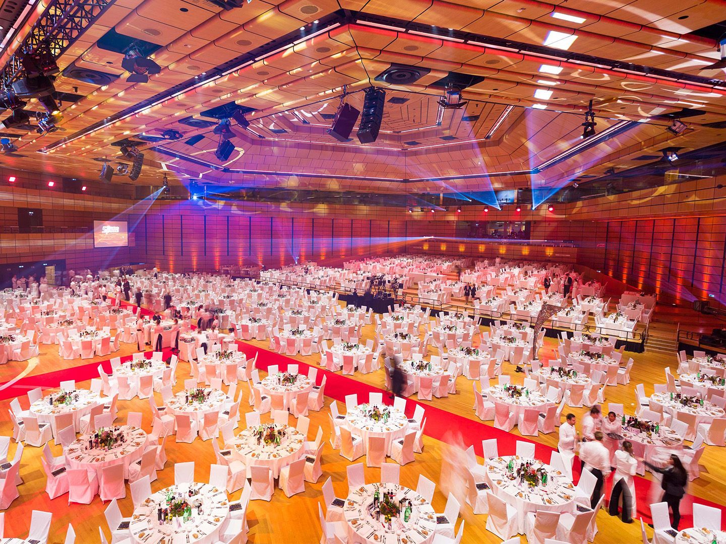 Large banquet hall with round tables covered in white cloth and chairs arranged for an event