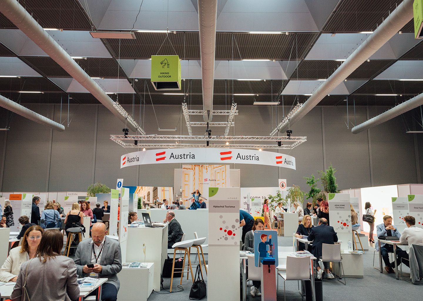 Trade fair booth with Austria branding and people sitting at tables in a large hall