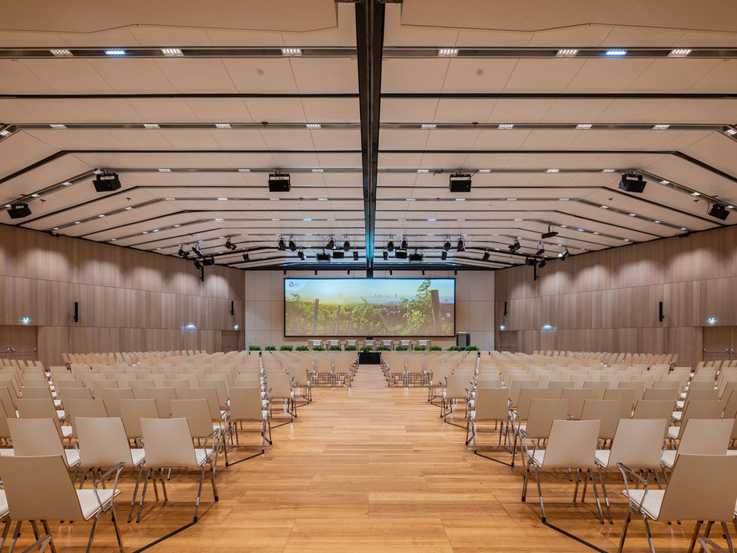 Leerer großer Konferenzraum mit Reihen von weißen Stühlen und großer Leinwand vorne
