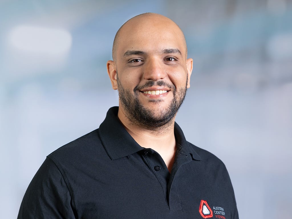 Person wearing a black polo shirt with Austria Center Vienna logo on the chest