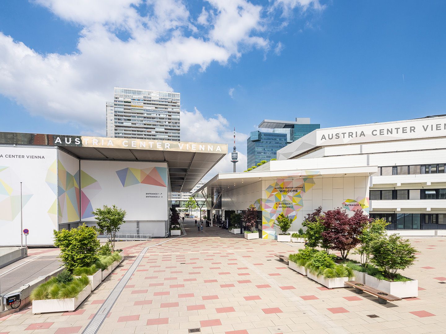 Eingangsbereich des Austria Center Vienna mit moderner Architektur und bepflanzten Sitzbereichen.