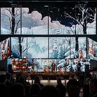 Große Fensterfront mit Blick auf verschneite Winterlandschaft und Bäume bei Nacht