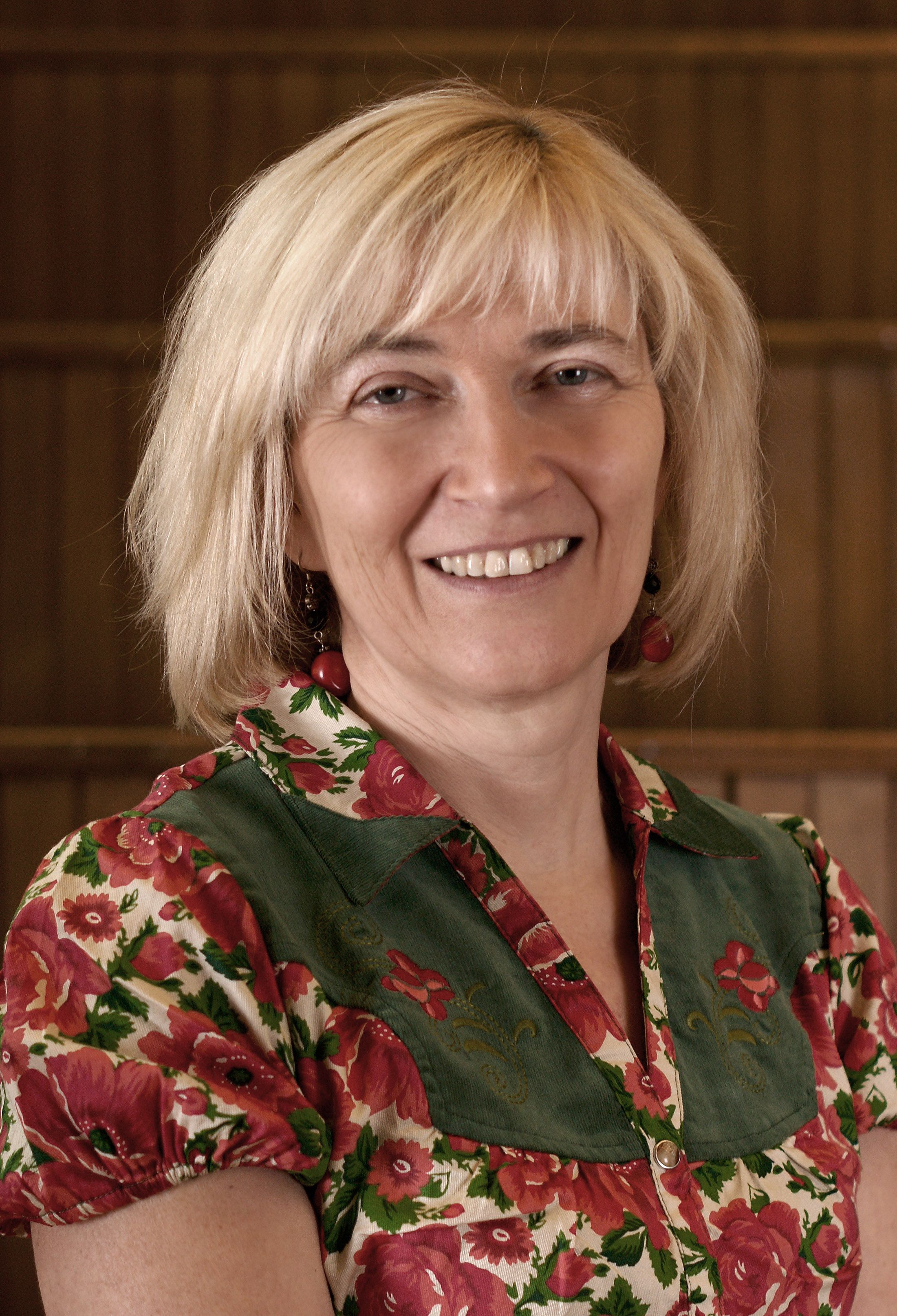 Portrait Doris Marko - Frau mit kurzen blonden Haaren und bunter Bluse
