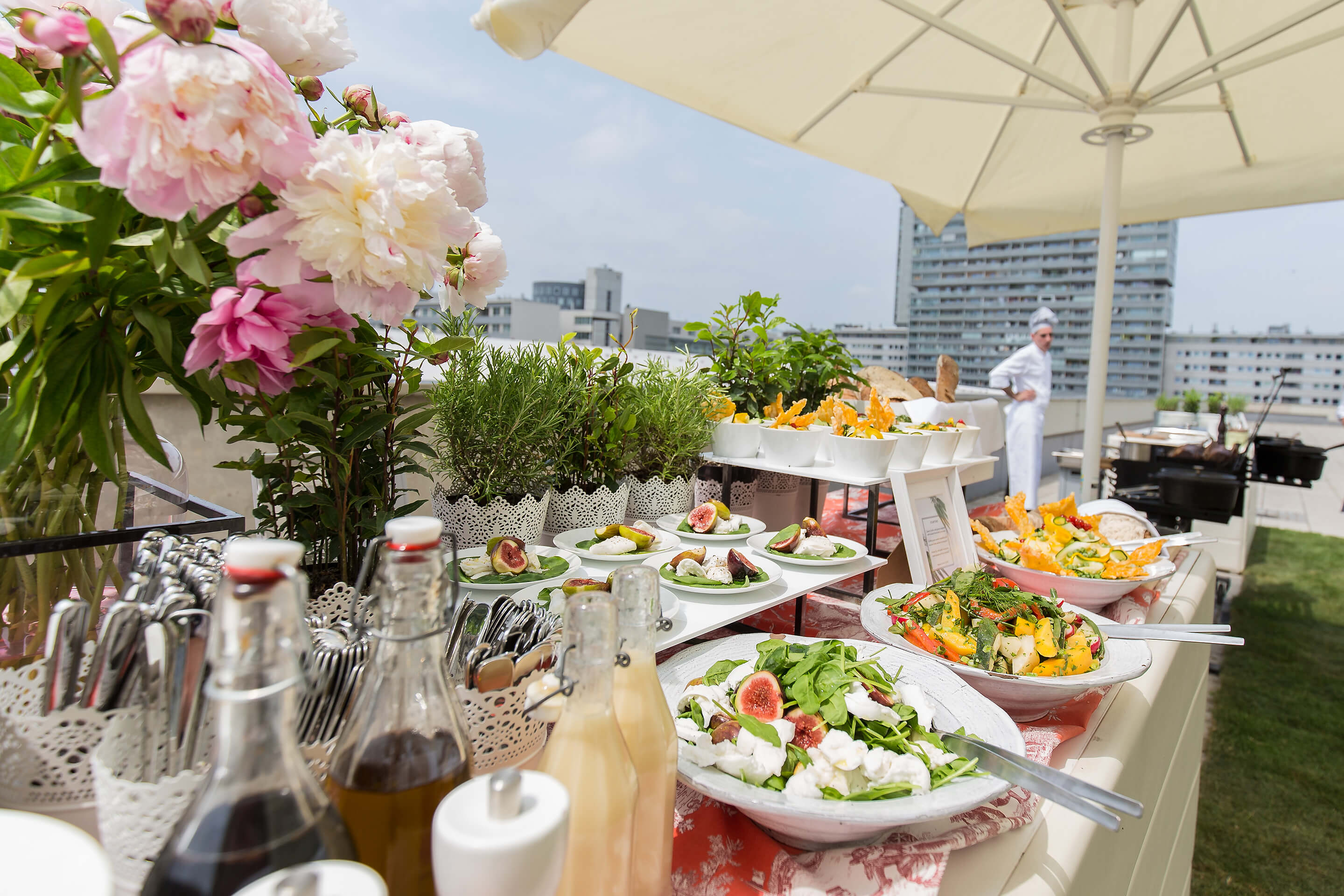 Foto: Buffetspeisen unter einem Sonnenschirm mit Koch und gruenem Rasen