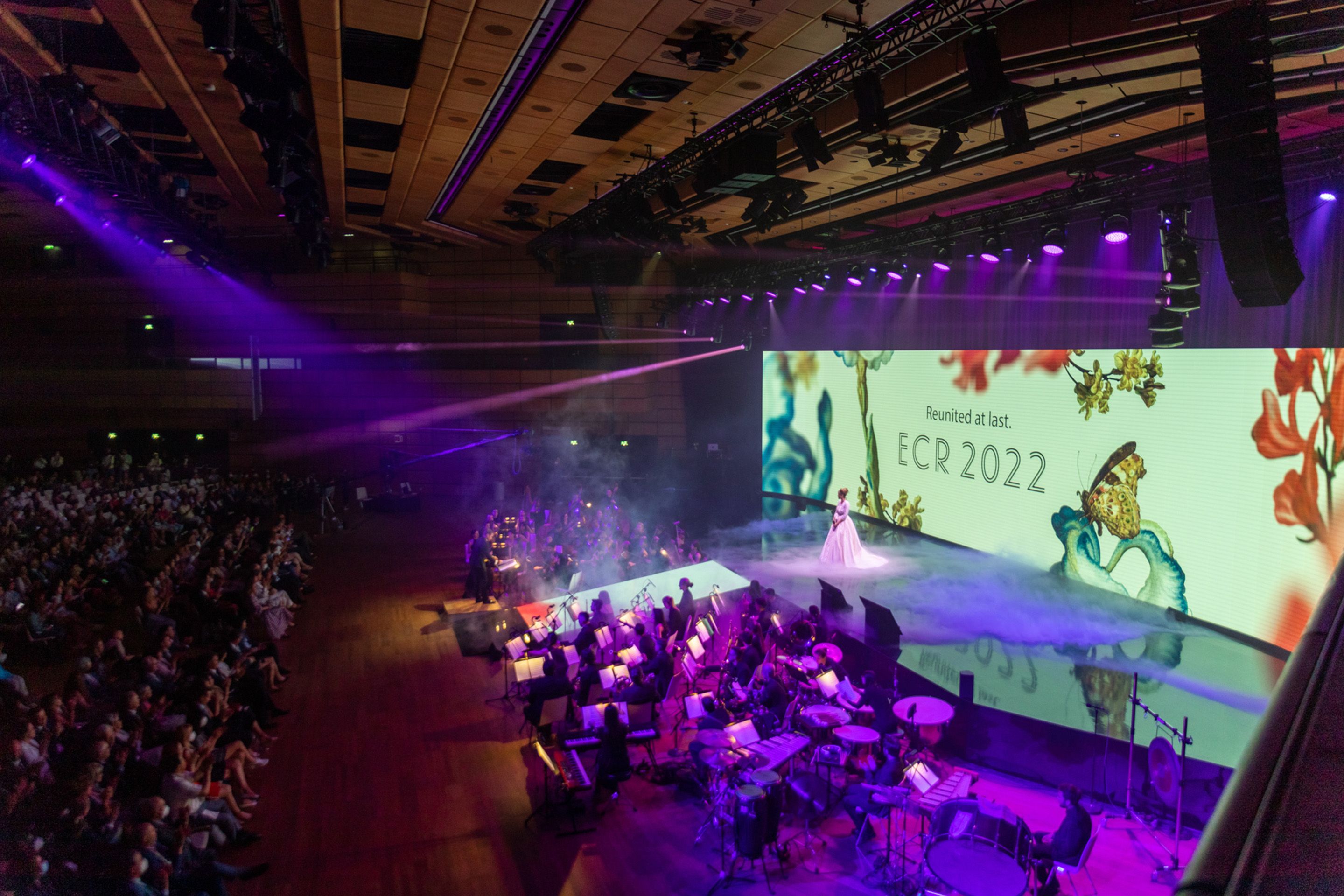 Foto: Sängerin auf Bühne mit dekorativem Hintergrund und Orchester