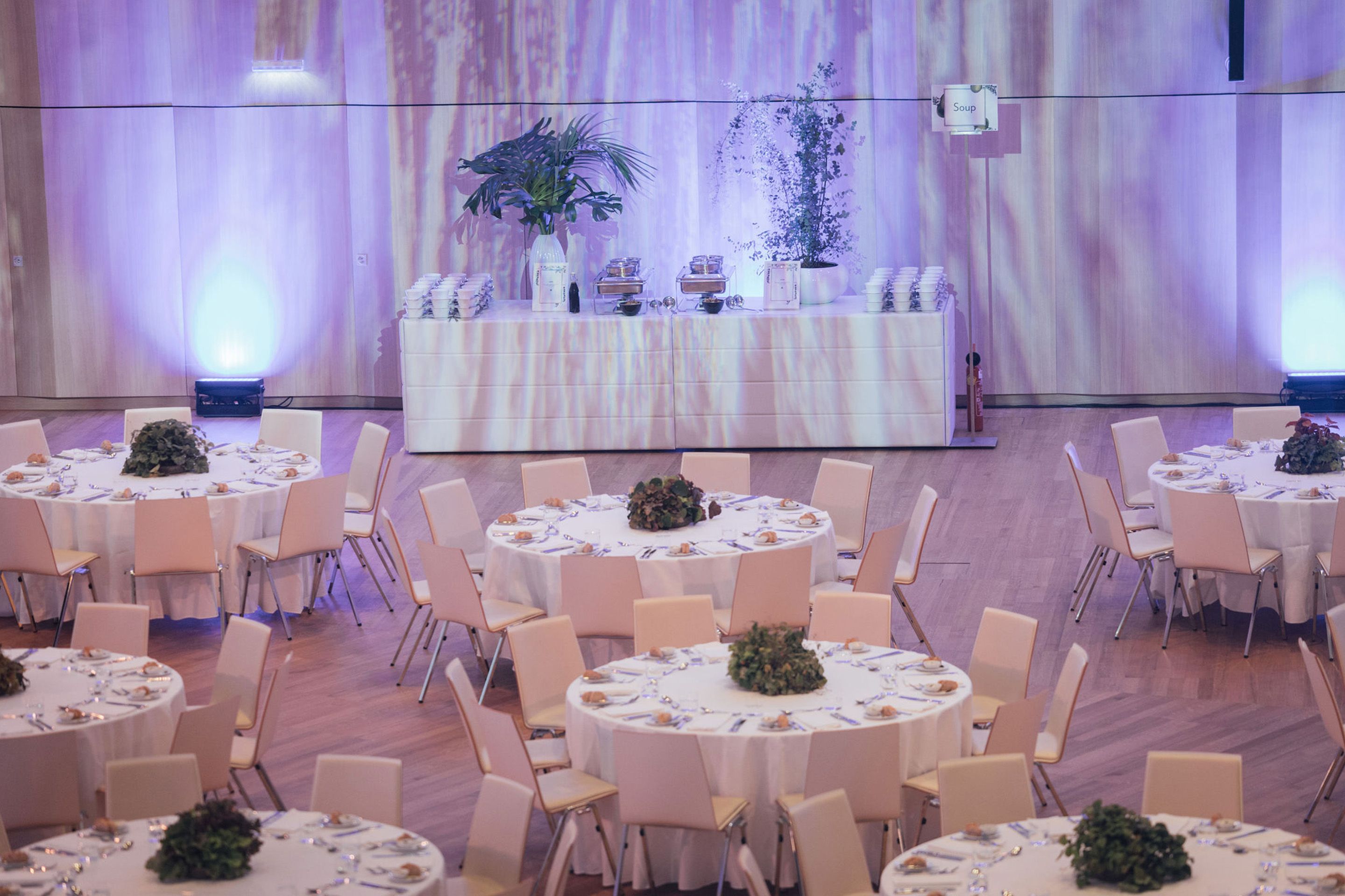 Foto: Runde Gala-Tische mit Stuehlen in einem Raum mit Buffet und Holzboden