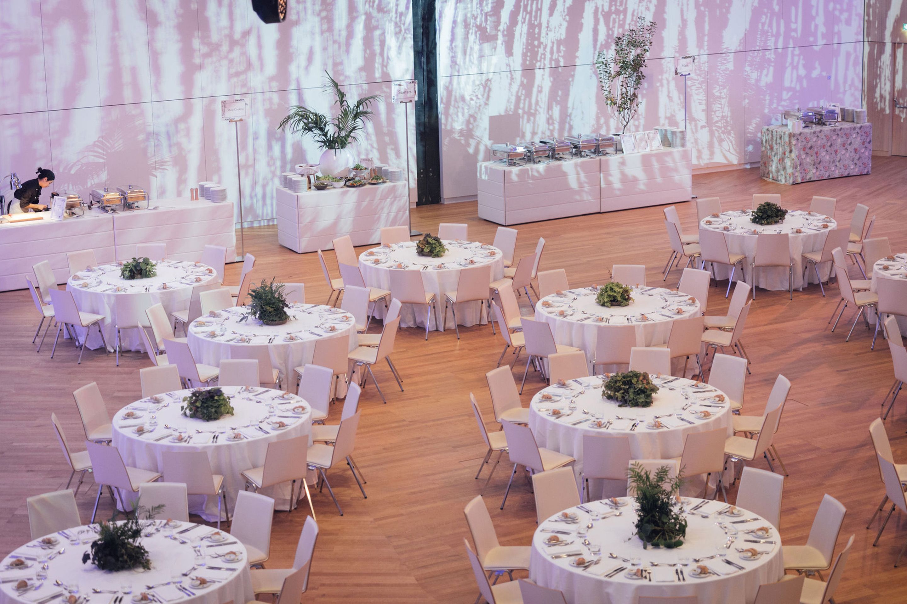 Foto: Runde Gala-Tische mit Stuehlen und Buffet in einem Raum mit Holzboden