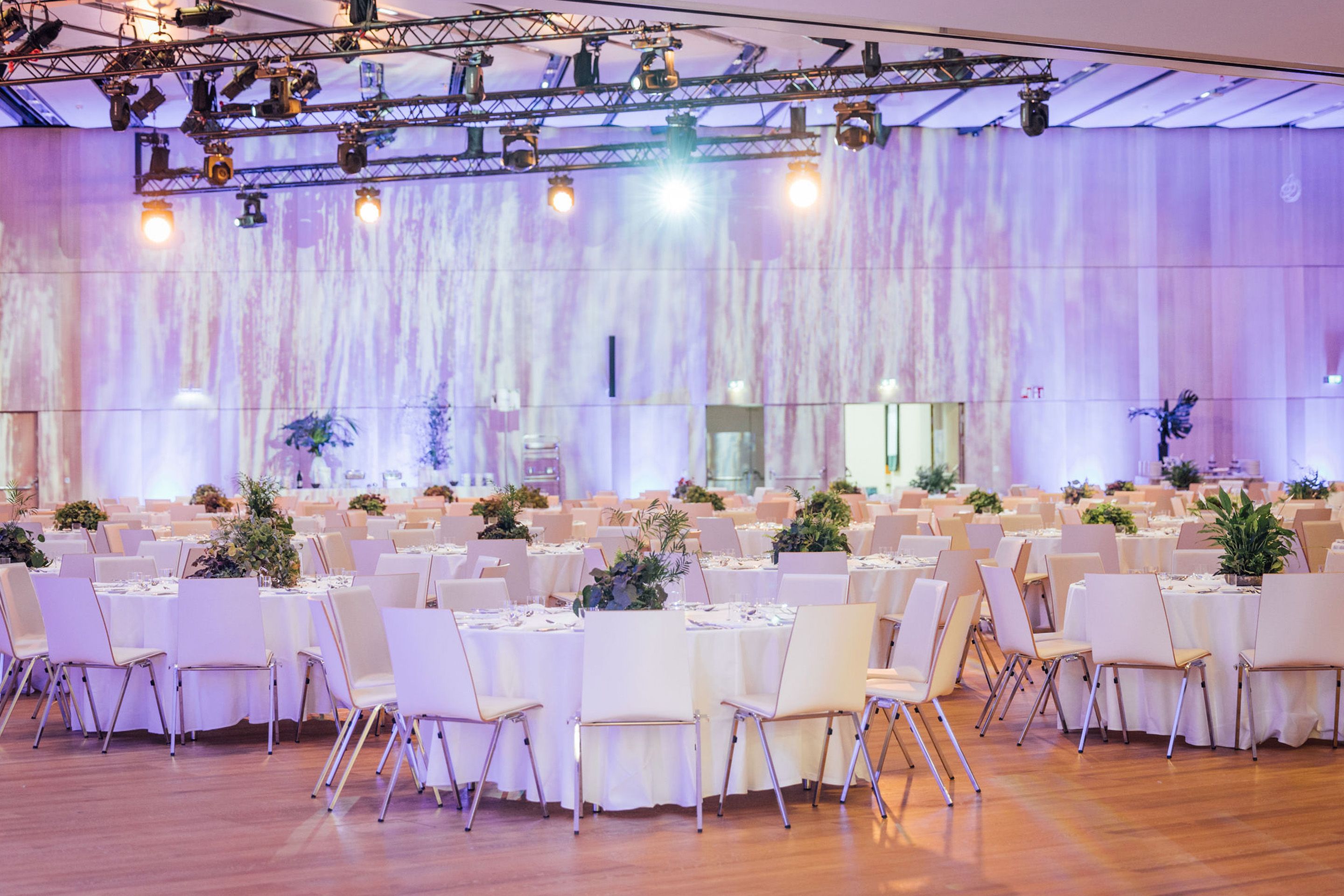 Foto: Runde Gala-Tische mit Stuehlen in einem Raum mit Holzboden