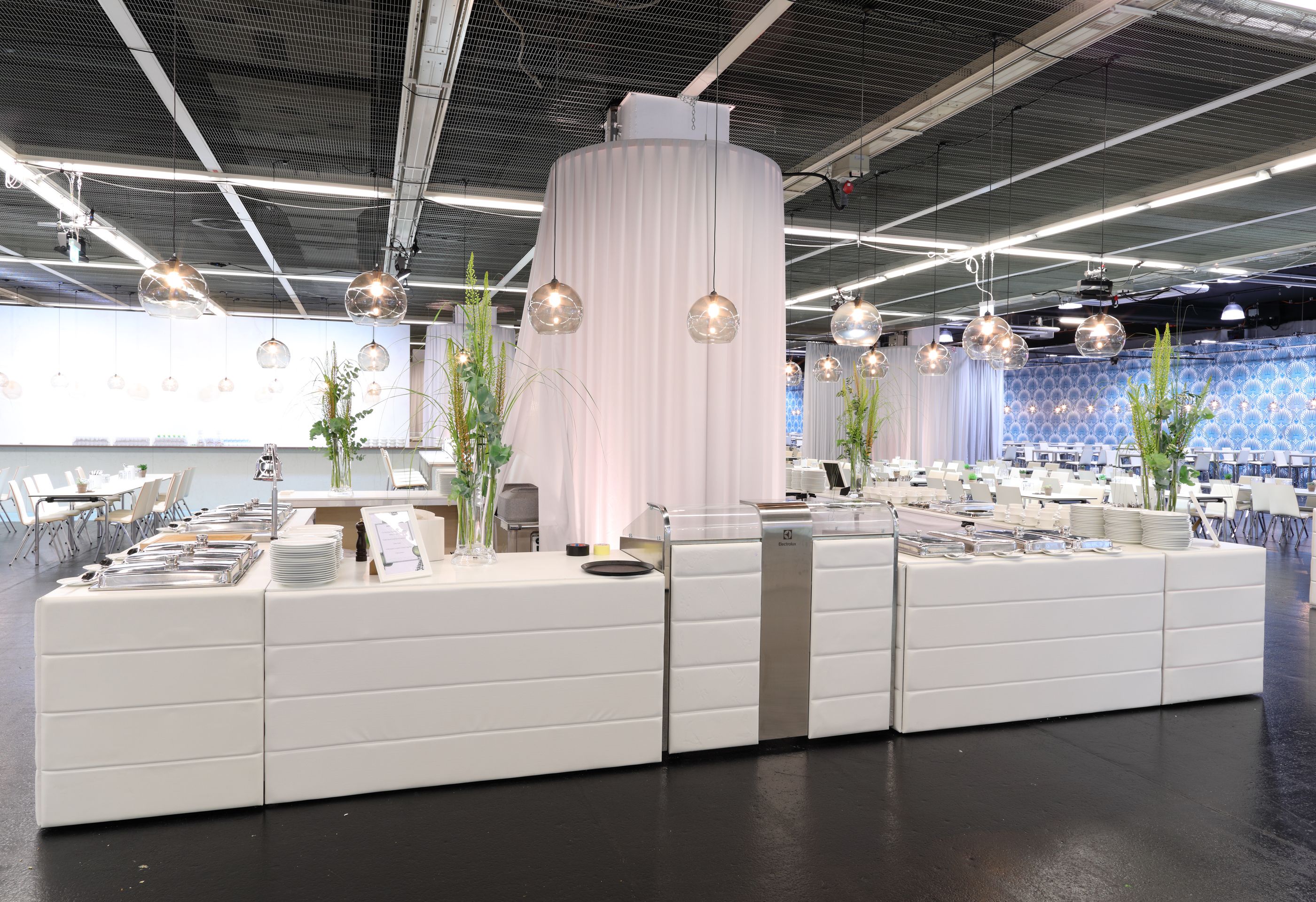 Foto: Weiße Tische mit Catering in einer dekorierten Halle