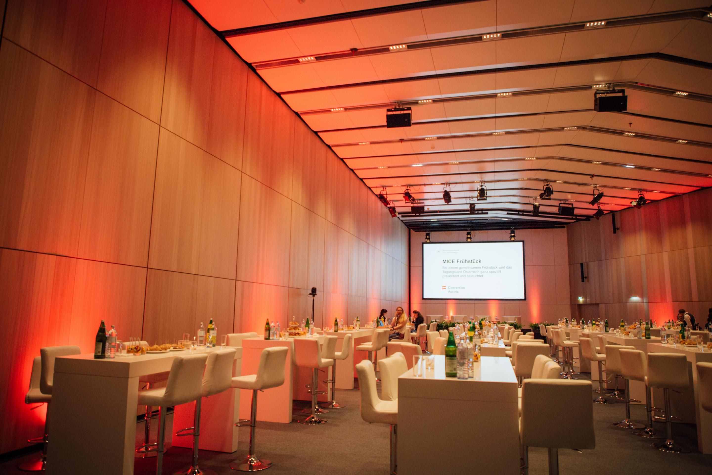 Foto: Saal mit Holzwaenden, Tischen und einer Leinwand