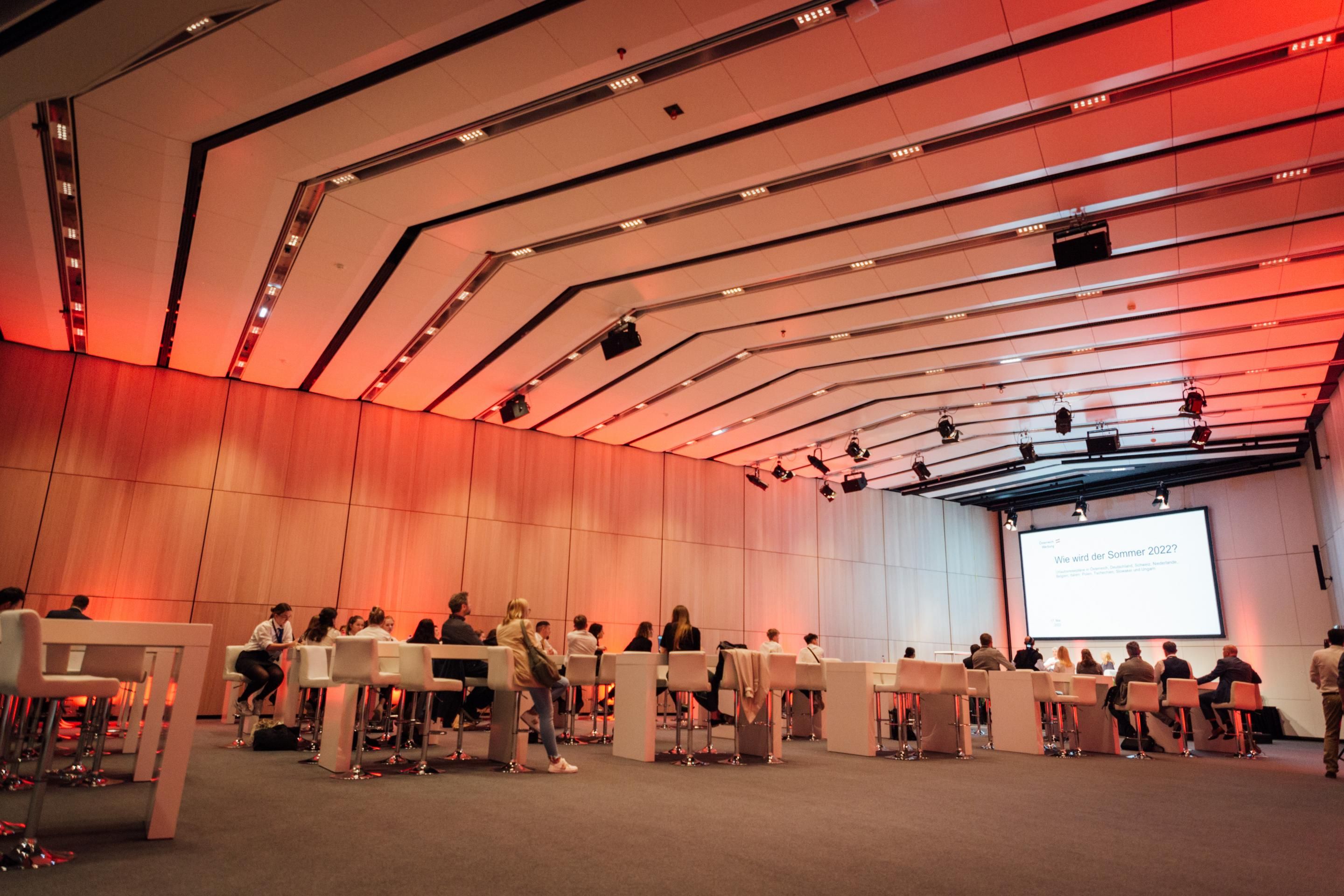 Foto: Saal mit Holzwaenden, Tischen und einer Leinwand