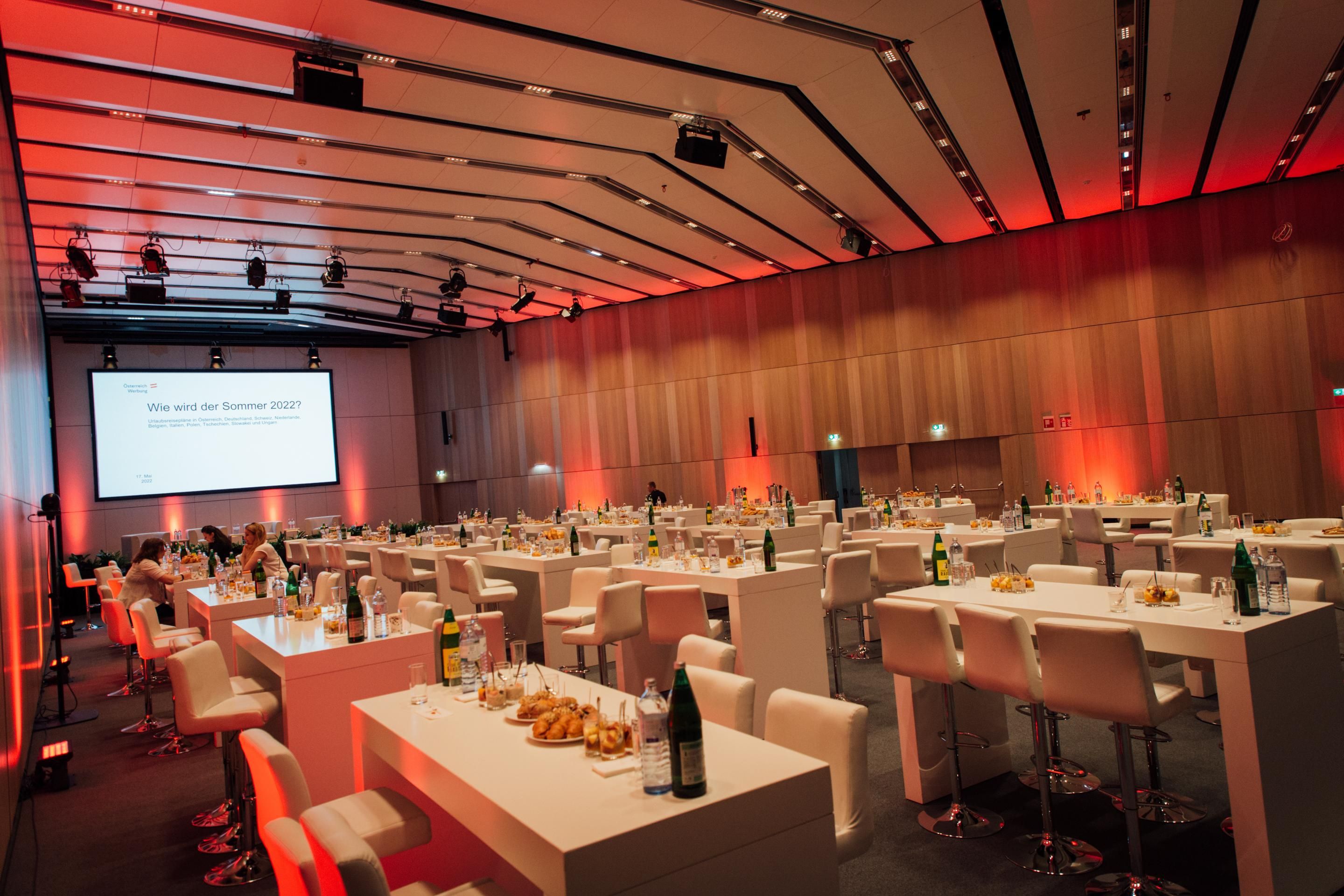Foto: Saal mit Holzwaenden, Tischen und einer Leinwand
