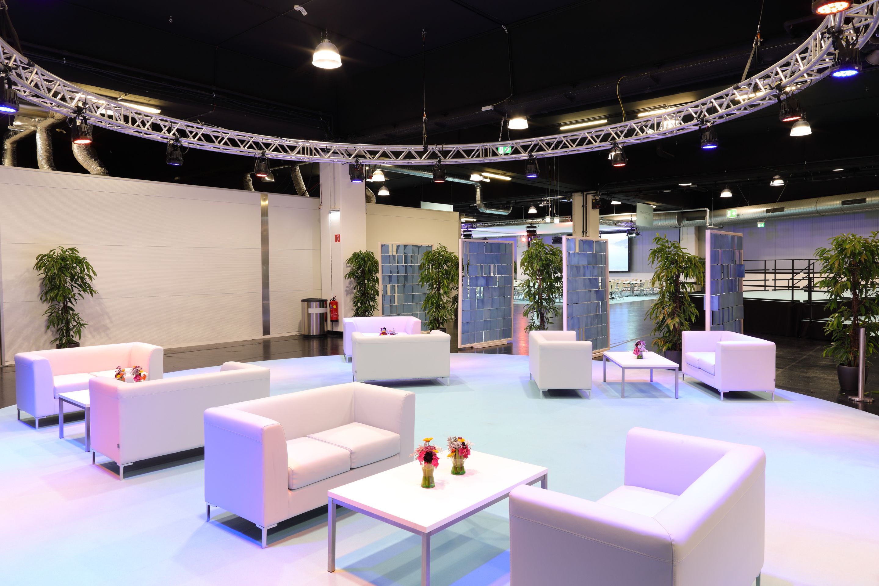 Foto: Weiße Tische, Sessel und Teppich in einer Halle mit schwarzer Decke