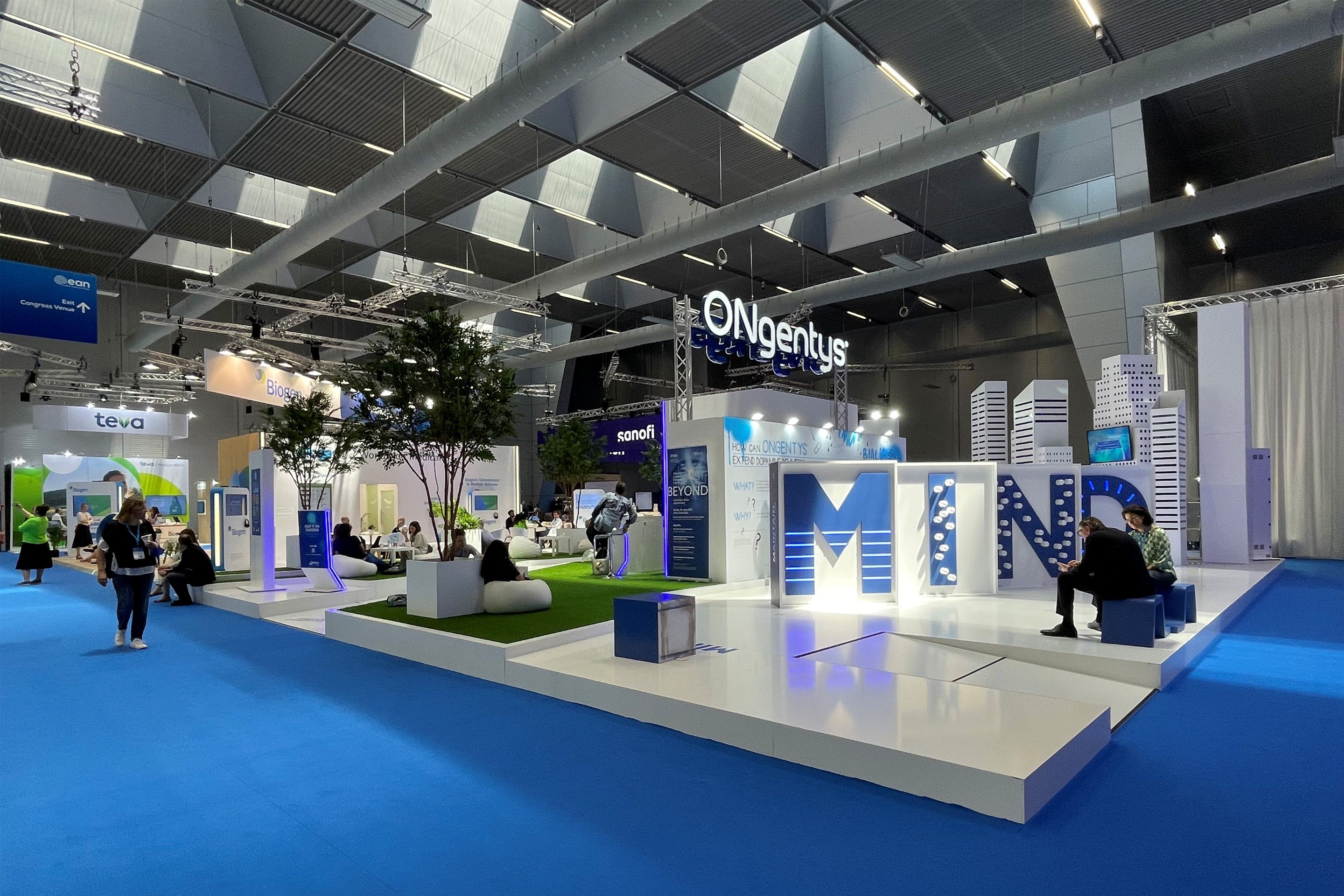 Foto: Helle Messestaende in einer Halle mit Menschen auf blauen Teppich