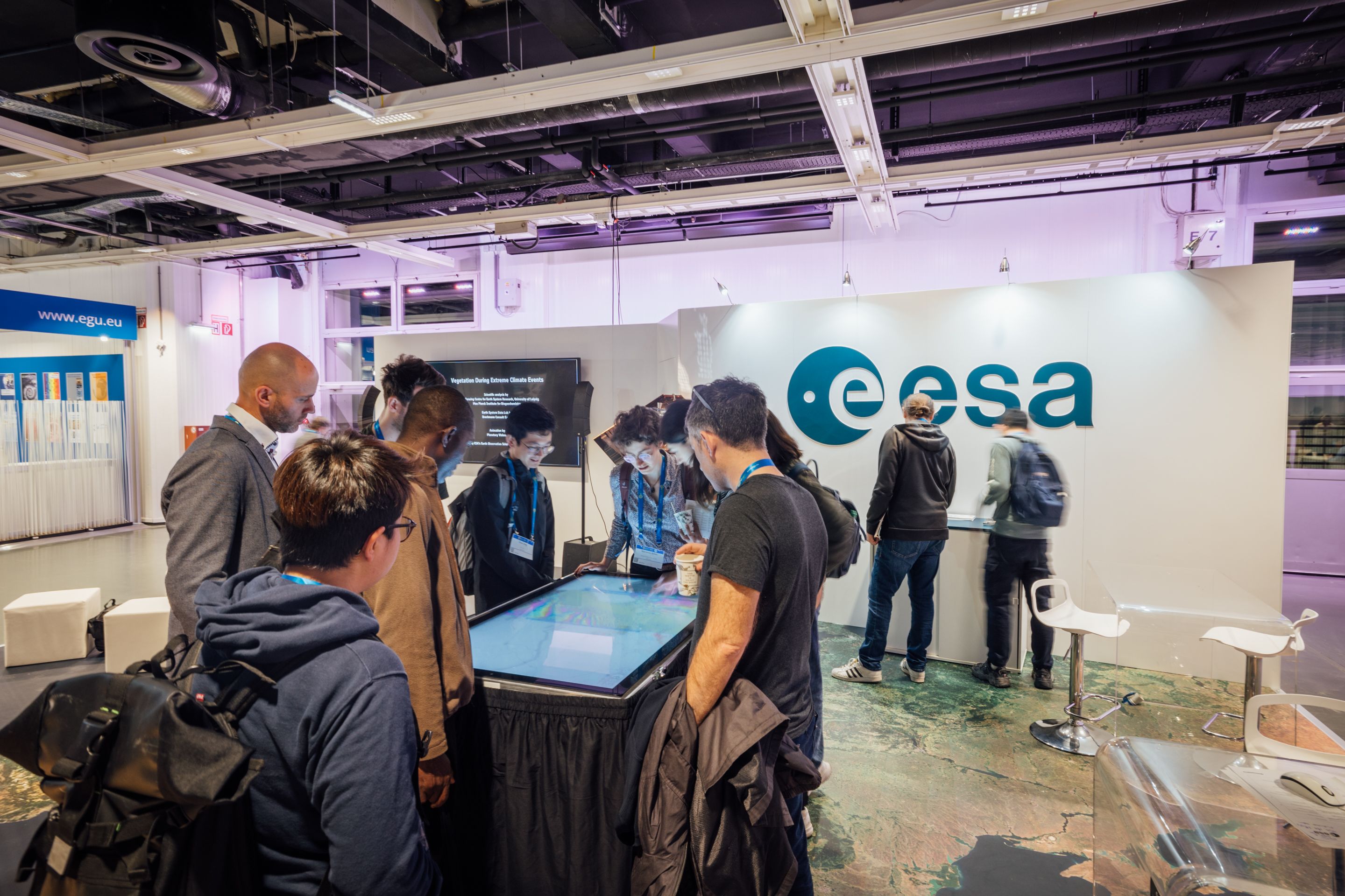 Foto: Menschen stehen um einen Ausstellungsstand mit Touchscreen